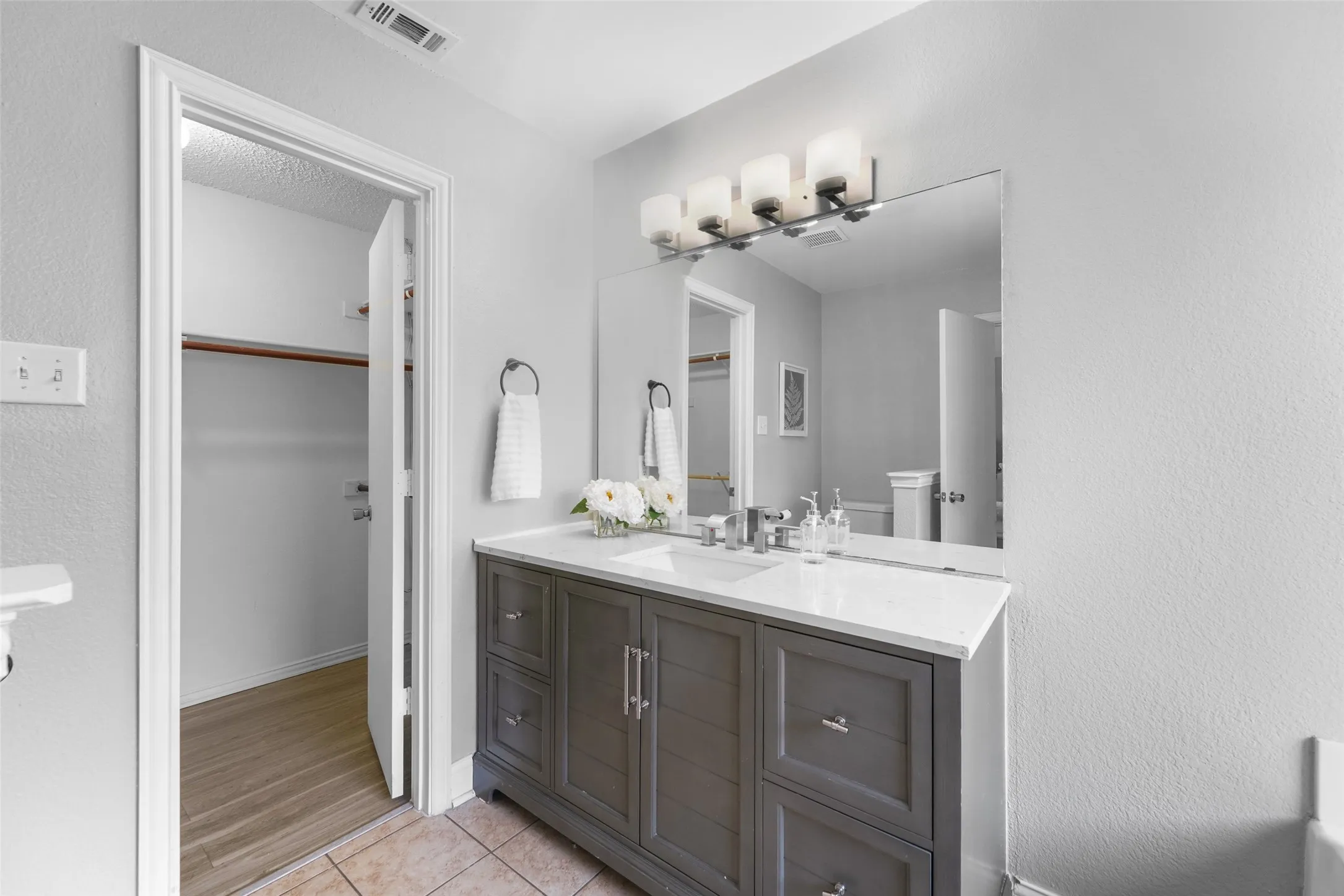 Bathroom featuring vanity, light tile patterned floors, a walk in closet, and a textured wall
