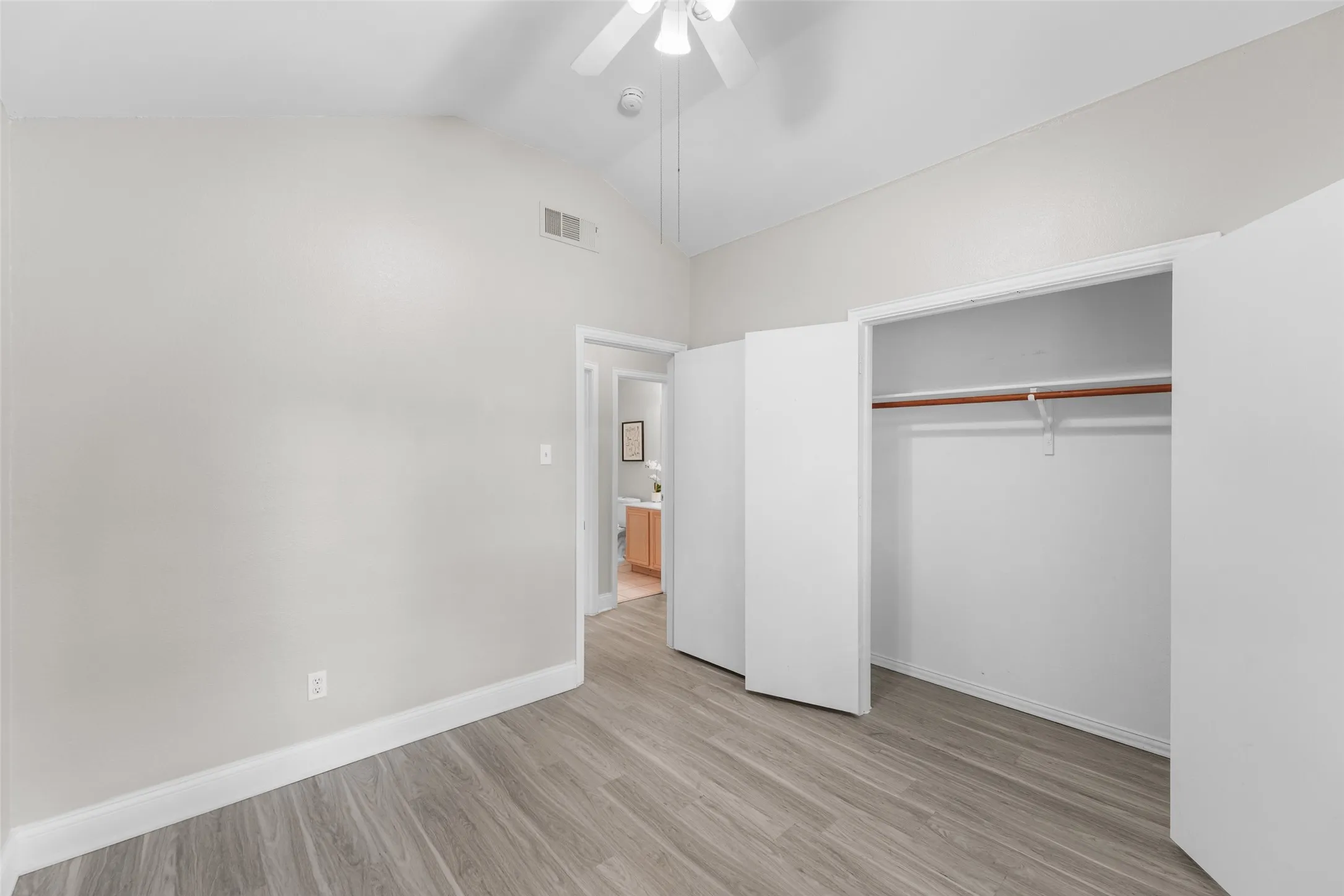 Unfurnished bedroom featuring vaulted ceiling, light wood finished floors, a closet, and ceiling fan