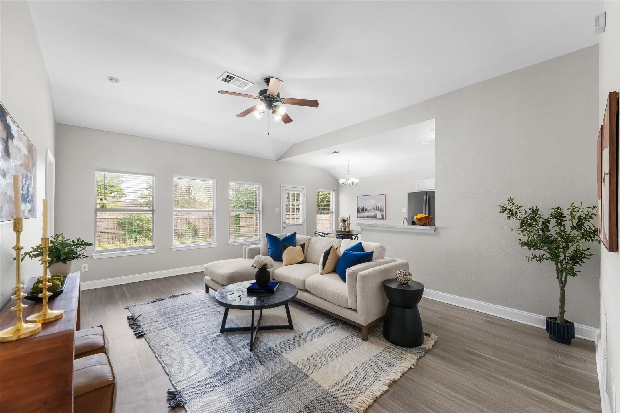 Virutally staged. Living area with ceiling fan, healthy amount of natural light, wood finished floors, and lofted ceiling