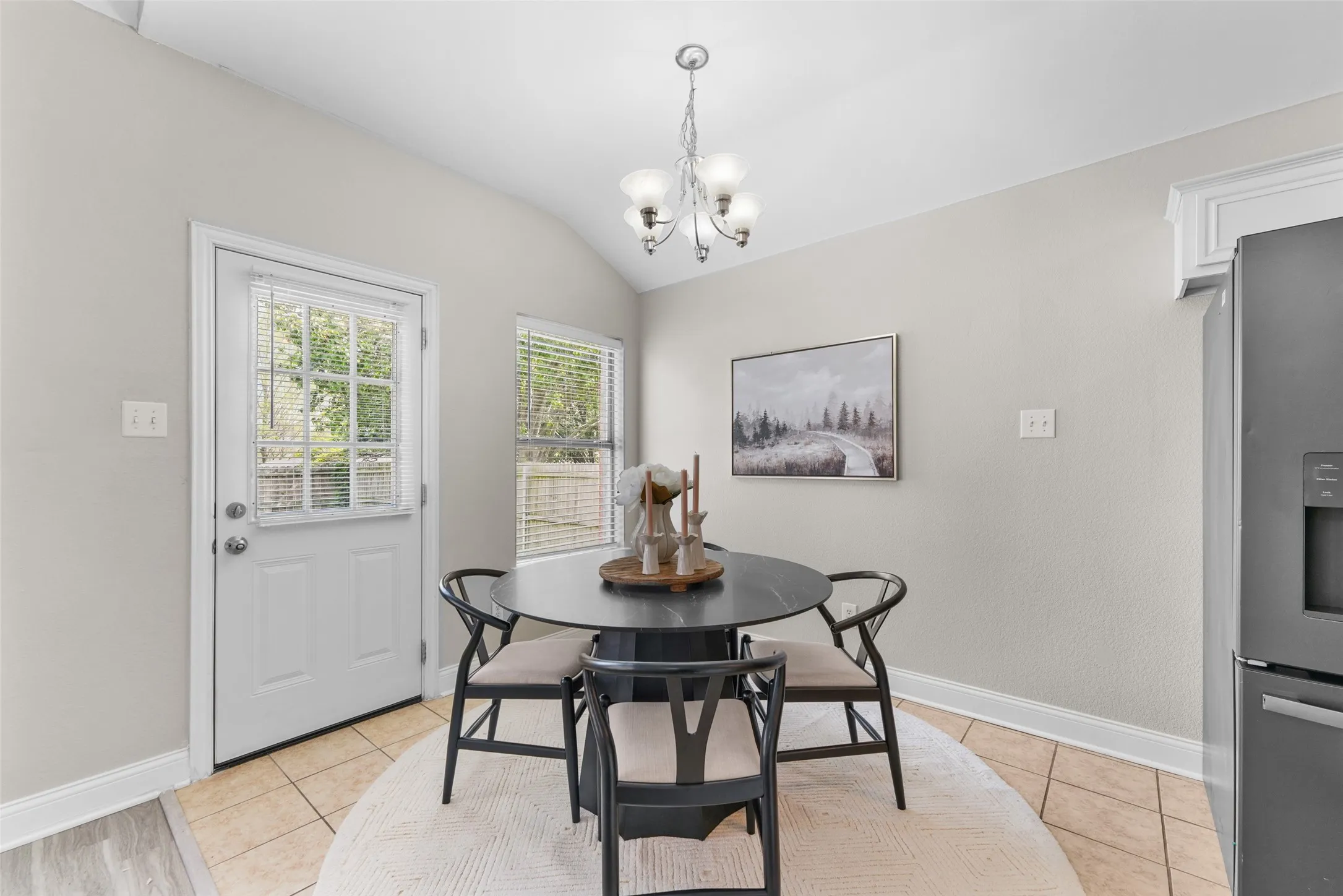 Virtually staged.Dining room featuring lofted ceiling, a chandelier, and light tile patterned floors