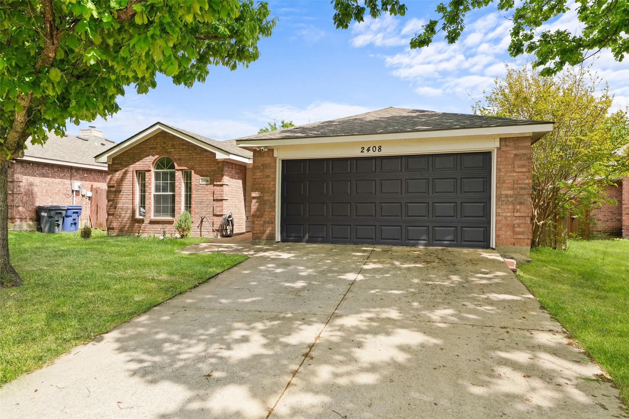 Single story home featuring a front yard, brick siding, driveway, and an attached garage