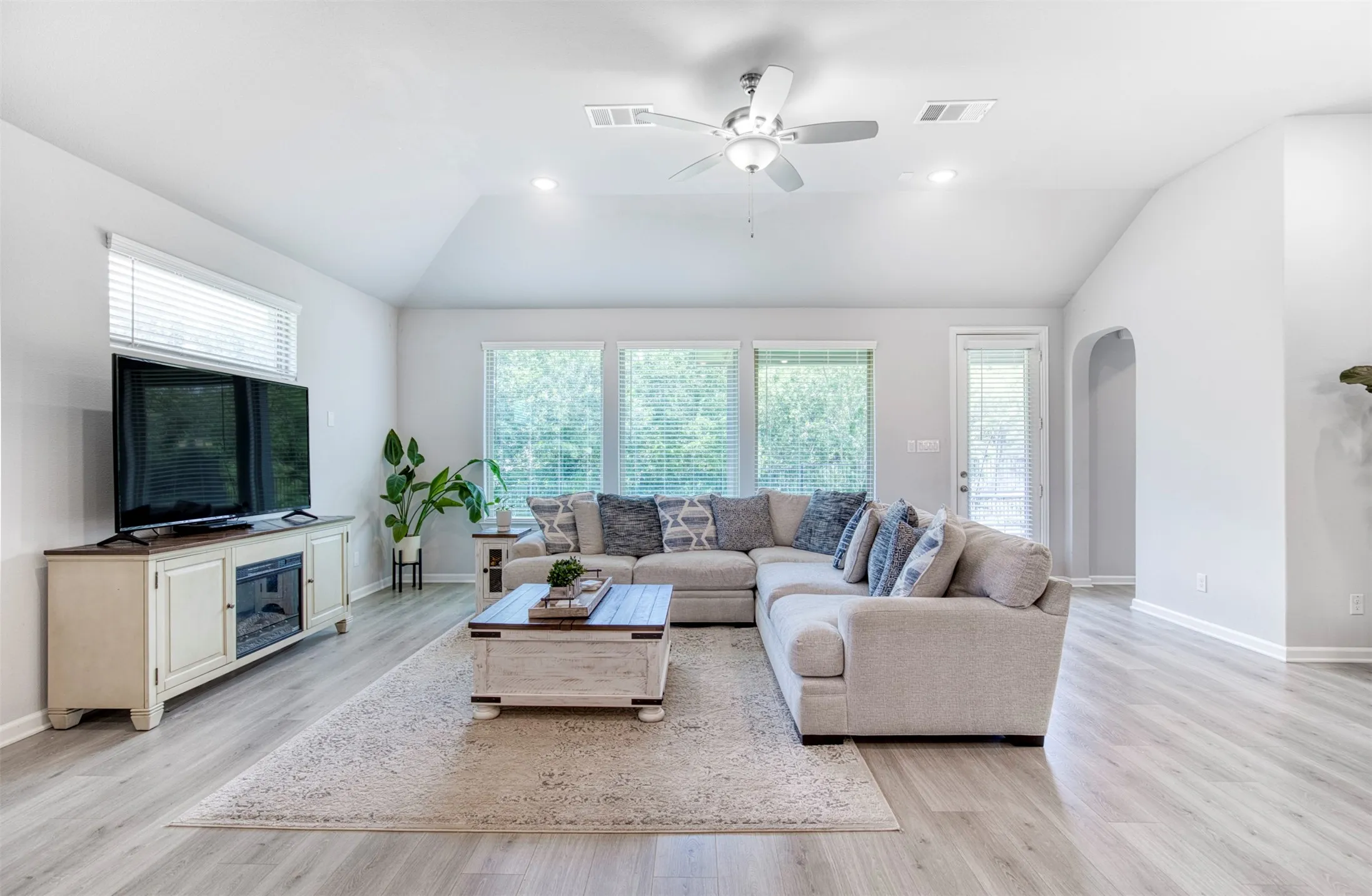 Spacious living room with sloped ceiling and ceiling fan.