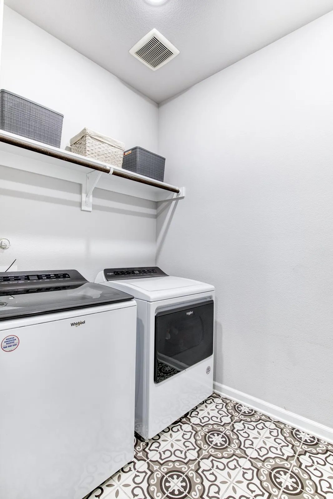 Laundry room with shelving and decorative floor tile.