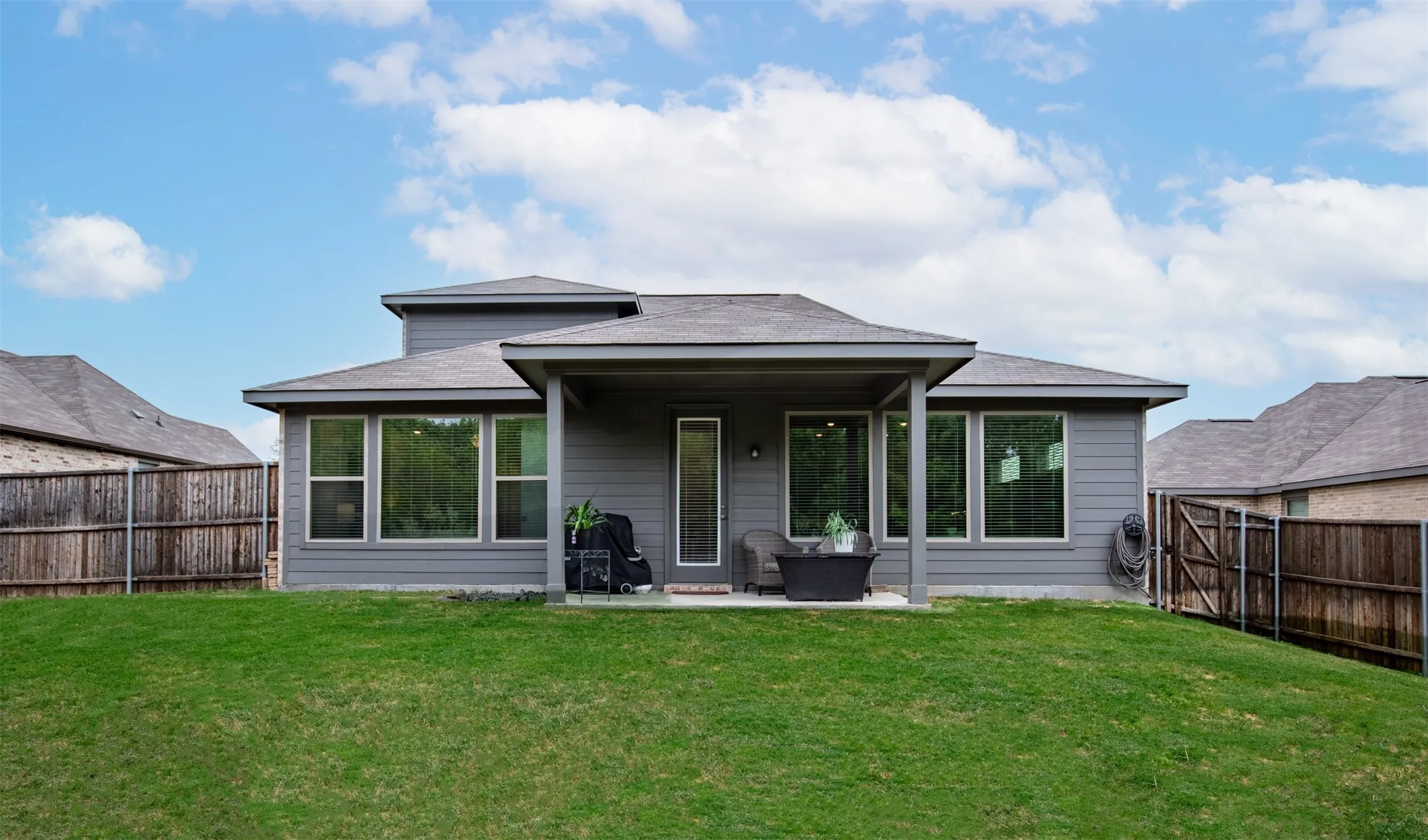 Covered patio and grassy yard surrounded by privacy fencing.