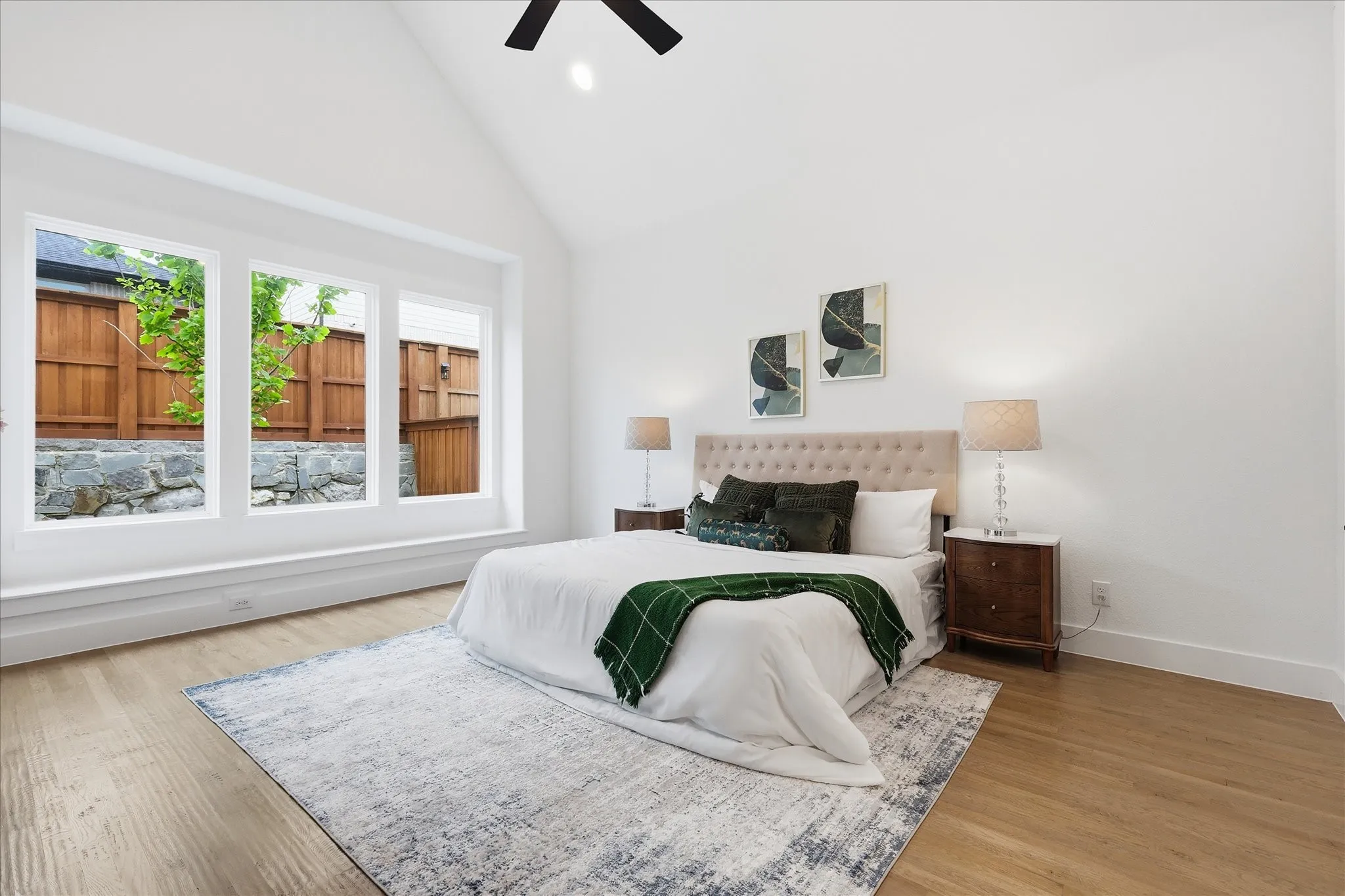 This room features a vaulted ceiling, light hardwood flooring, and a large bank of windows