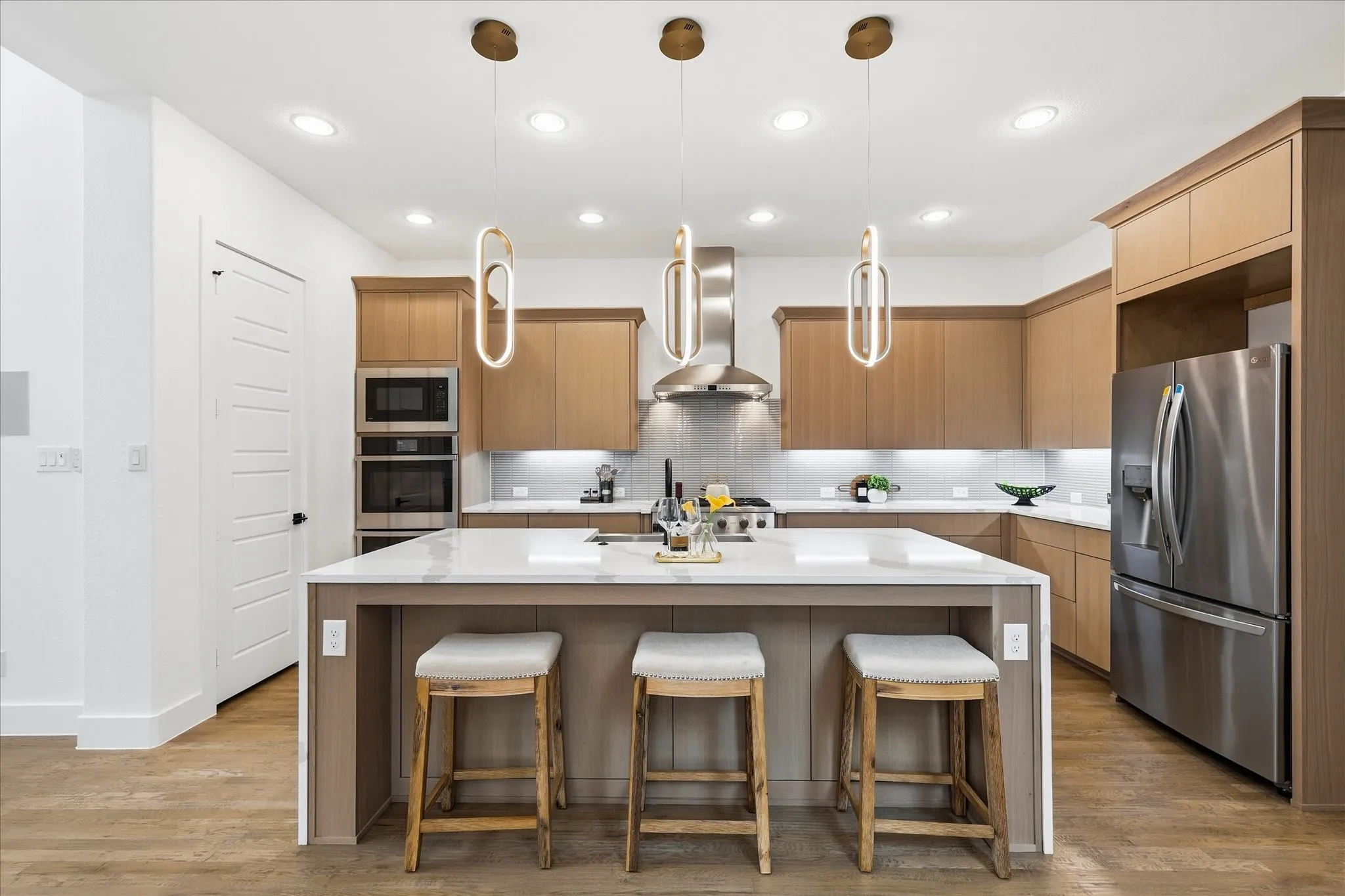 Modern kitchen featuring a large central island with seating, stainless steel appliances, and sleek cabinetry