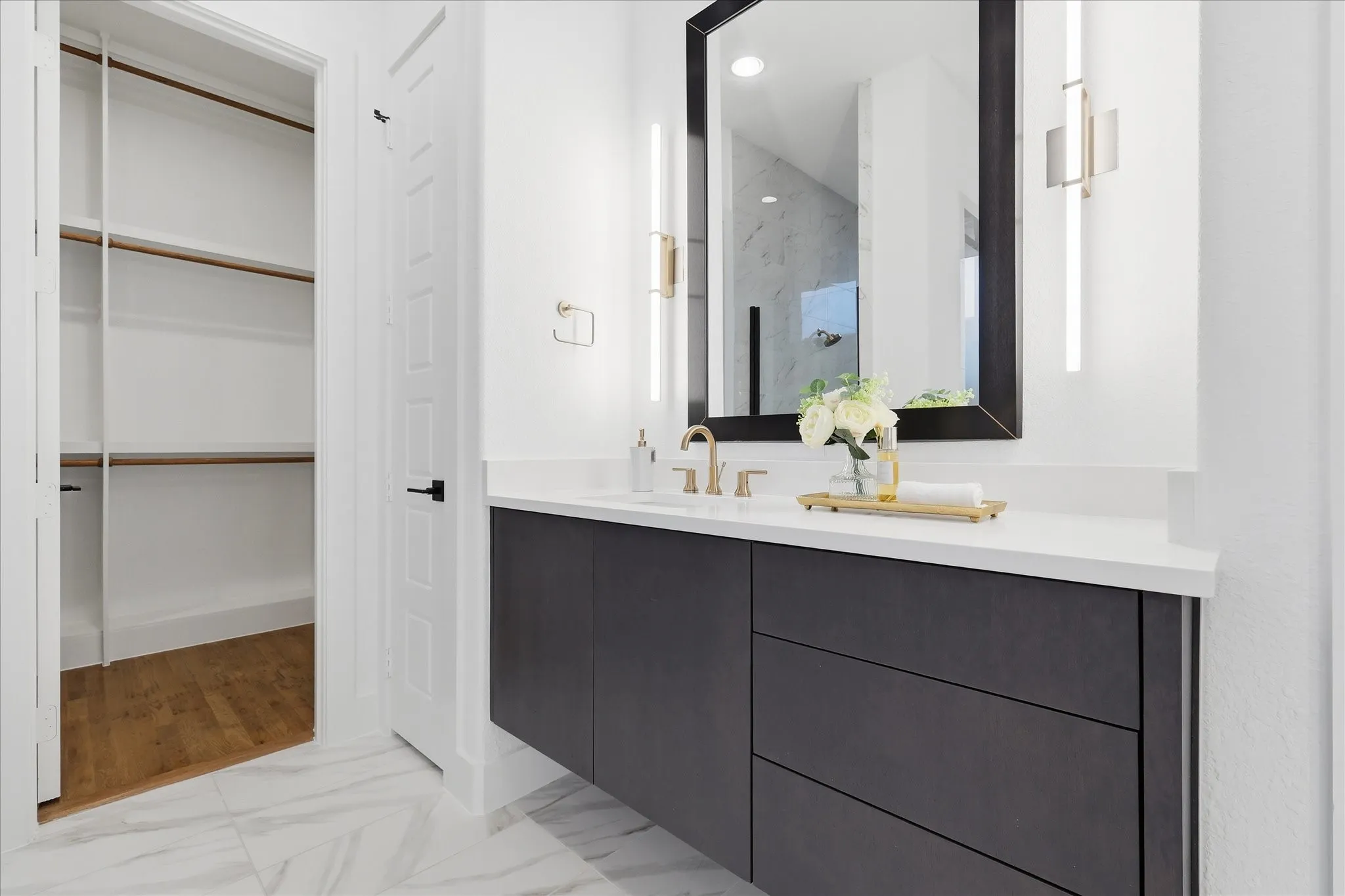 Bathroom featuring a vanity with dark cabinetry, a white countertop, and a large mirror with integrated lighting