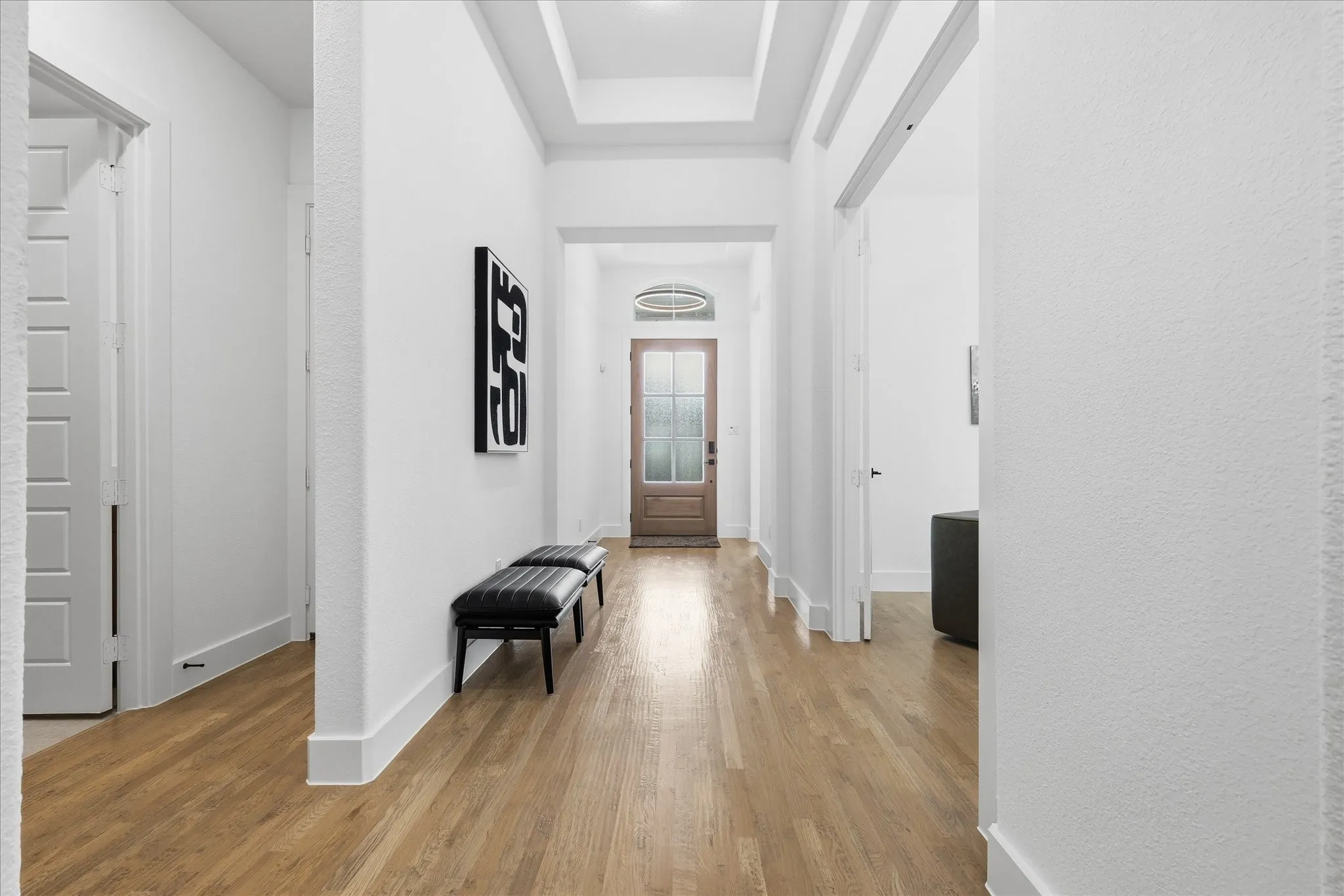 Entryway featuring warm-toned wood flooring, white walls, and a decorative ceiling