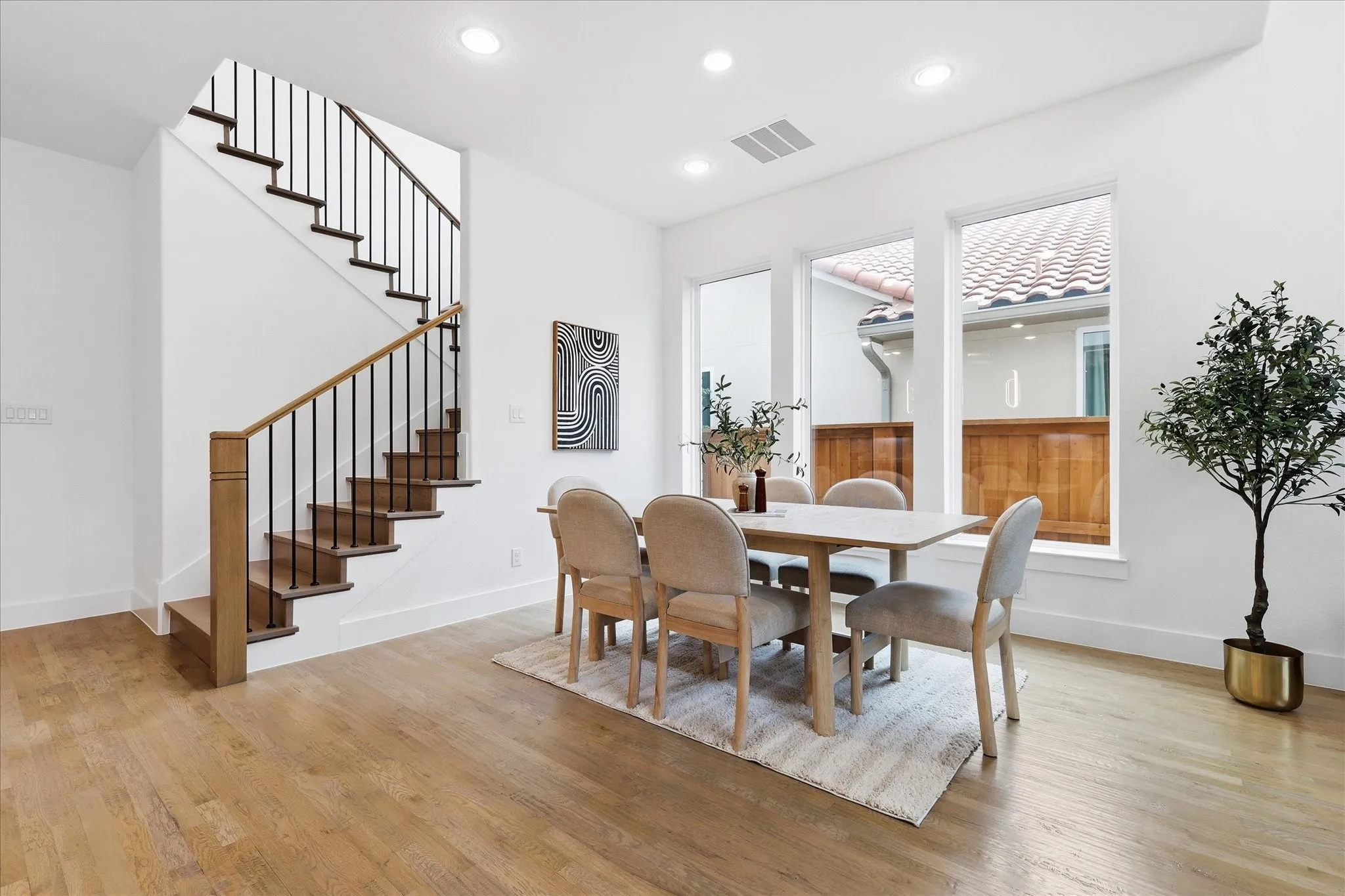 This bright interior space features hardwood floors, a staircase with wood treads and a black metal railing, and white walls