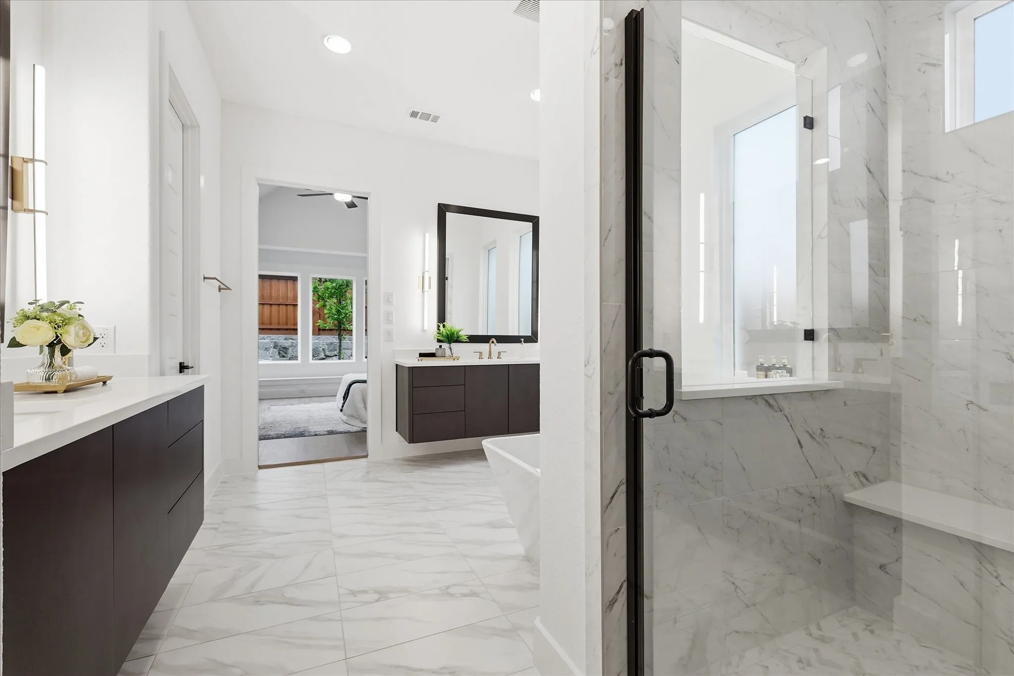 This bathroom features marble-look tile flooring, white walls, and dark cabinetry with white countertops
