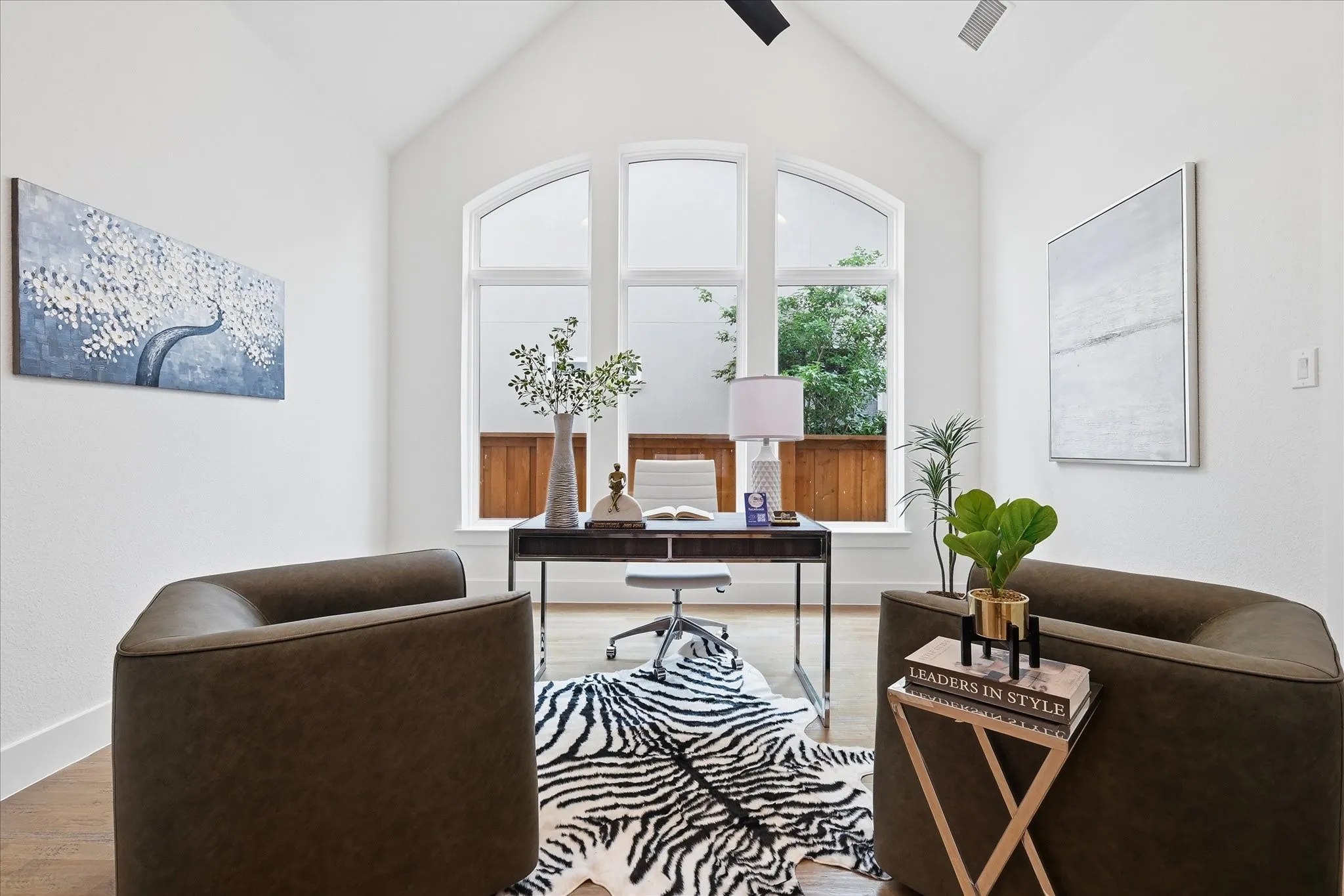 The property features a room with vaulted ceilings, large arched windows, and light hardwood floors