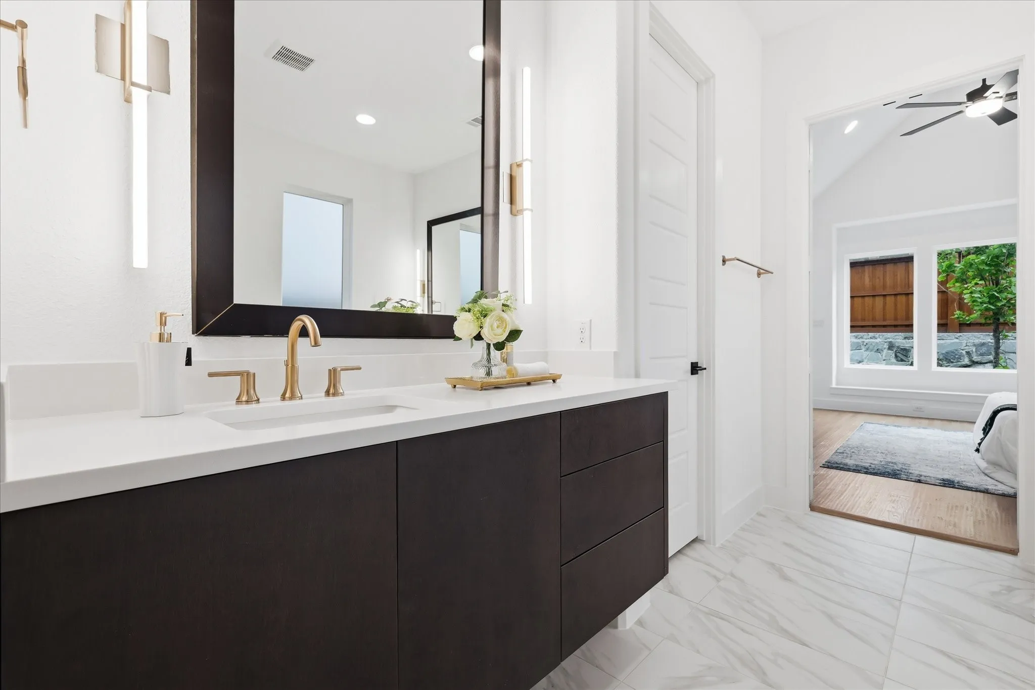 Bathroom vanity featuring a white countertop with a rectangular sink and gold-toned faucet