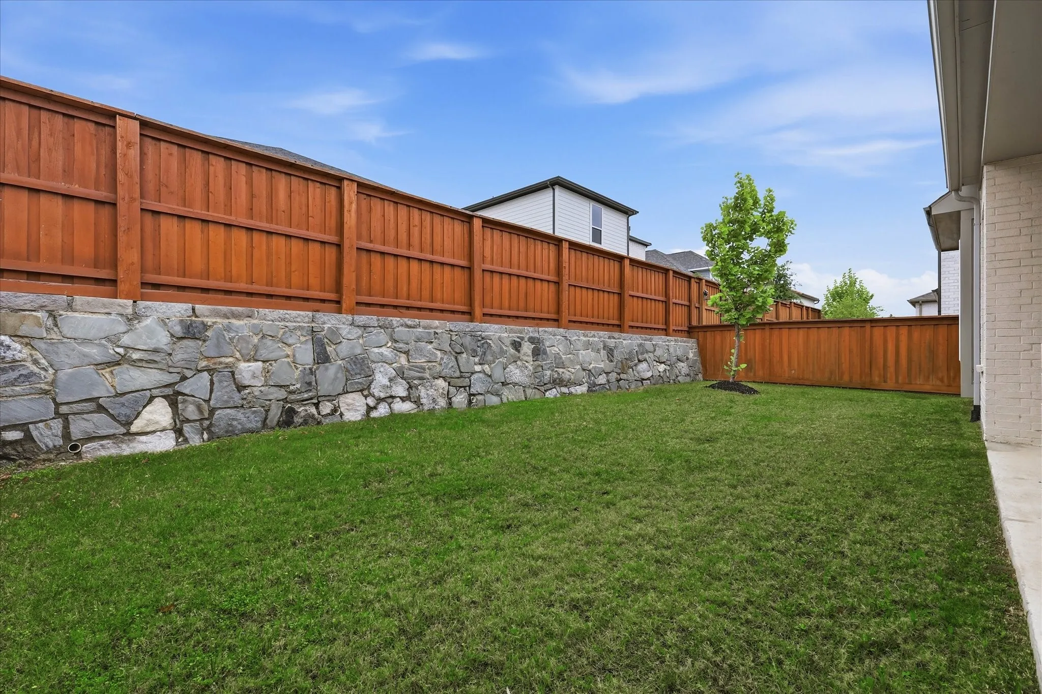 The property features a spacious backyard with a well-maintained lawn and a young tree