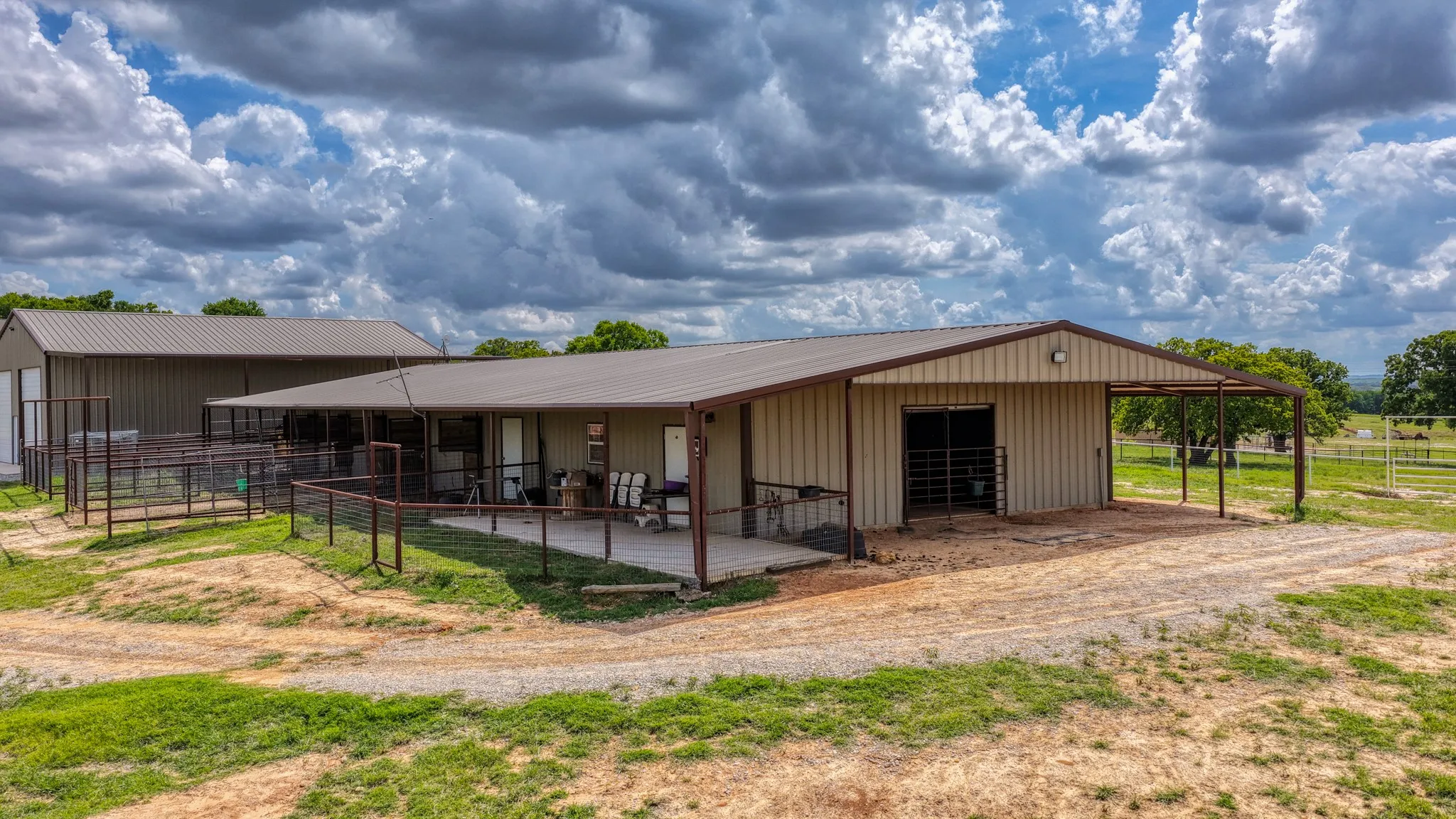 The property features two metal buildings with covered overhangs and a fenced area