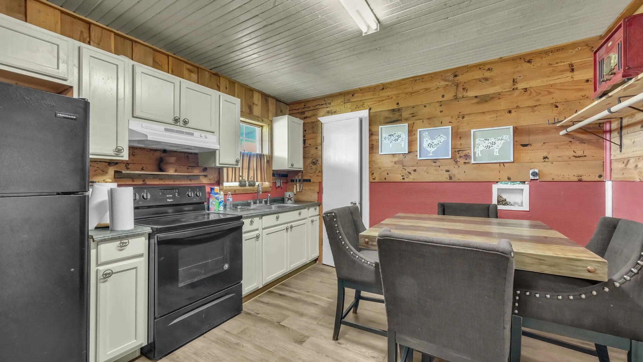 The kitchen features white cabinetry, a black range, and a black refrigerator