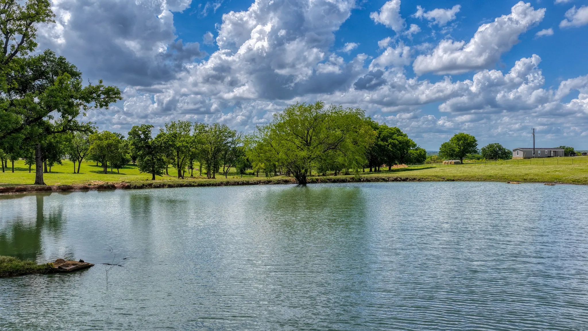 The property features a tranquil pond surrounded by lush green landscapes and mature trees, offering a serene outdoor setting