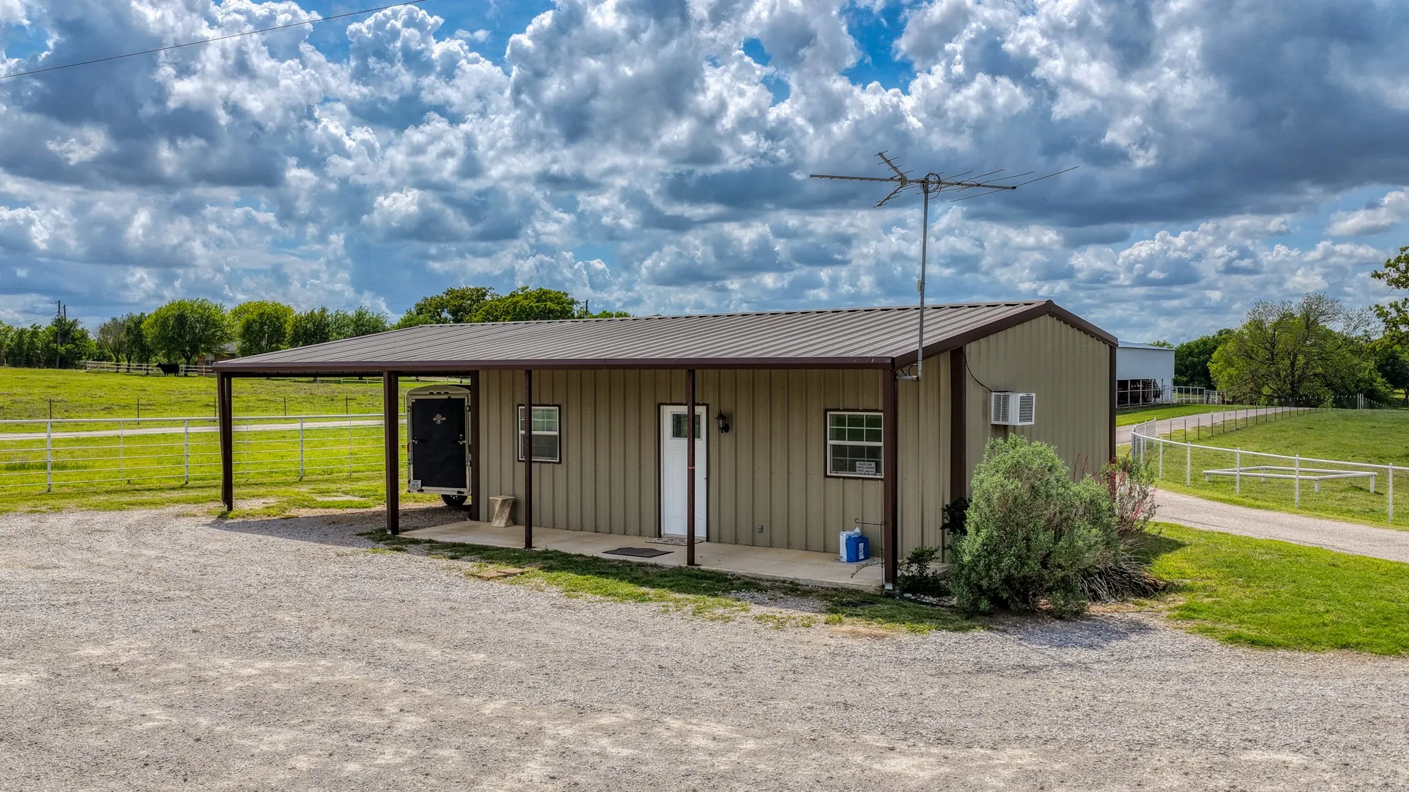 The property features a metal building with a covered porch and an extended carport area