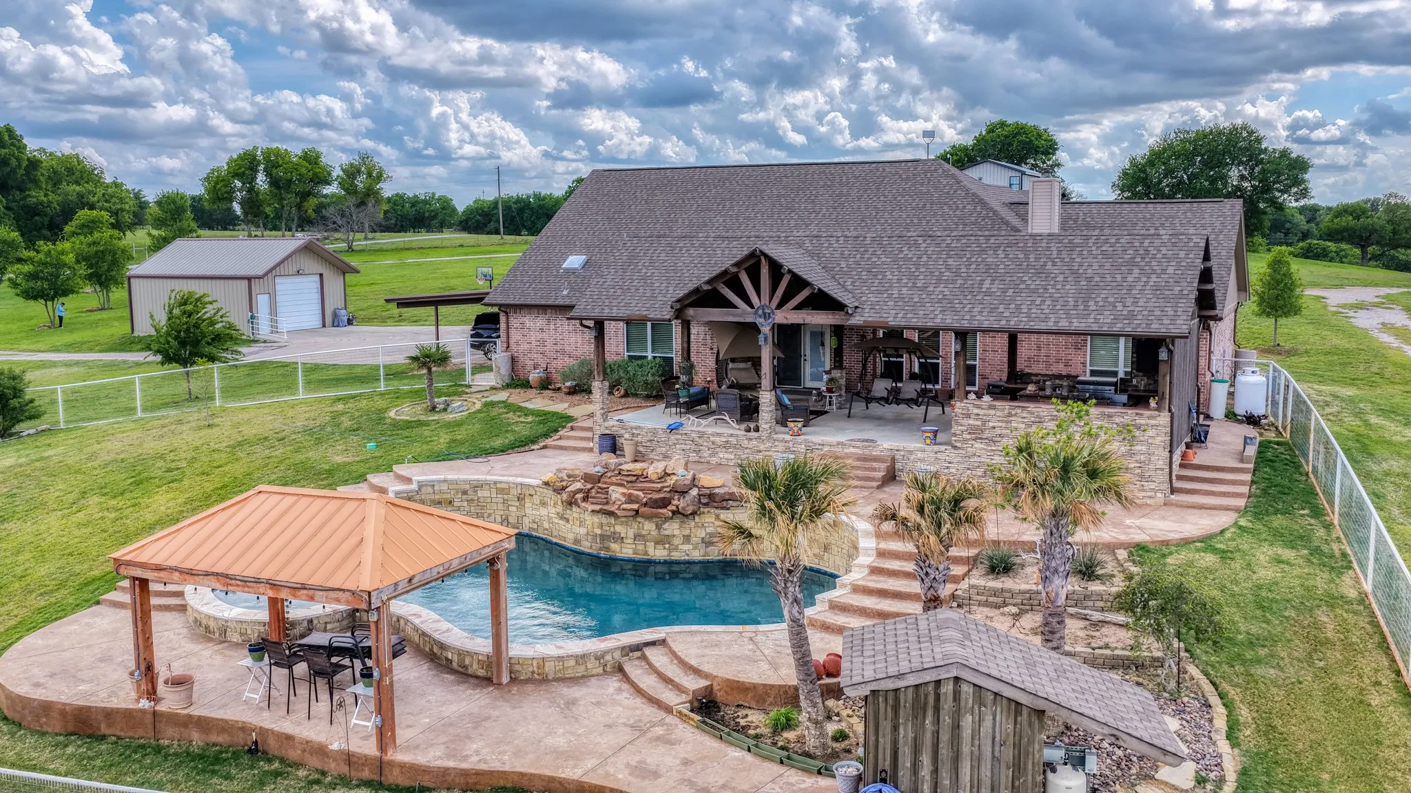 The property features an extensive backyard with a swimming pool, a covered patio area, and a separate garage building
