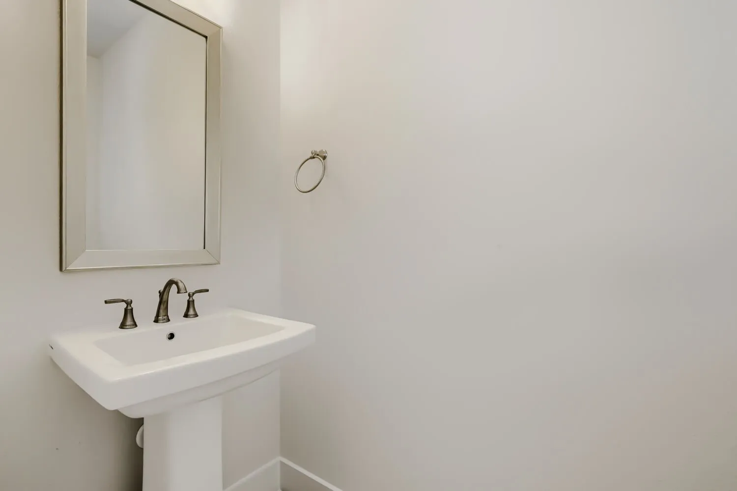 Pedestal sink with a wide basin, bronze-finish faucet, and coordinating towel ring