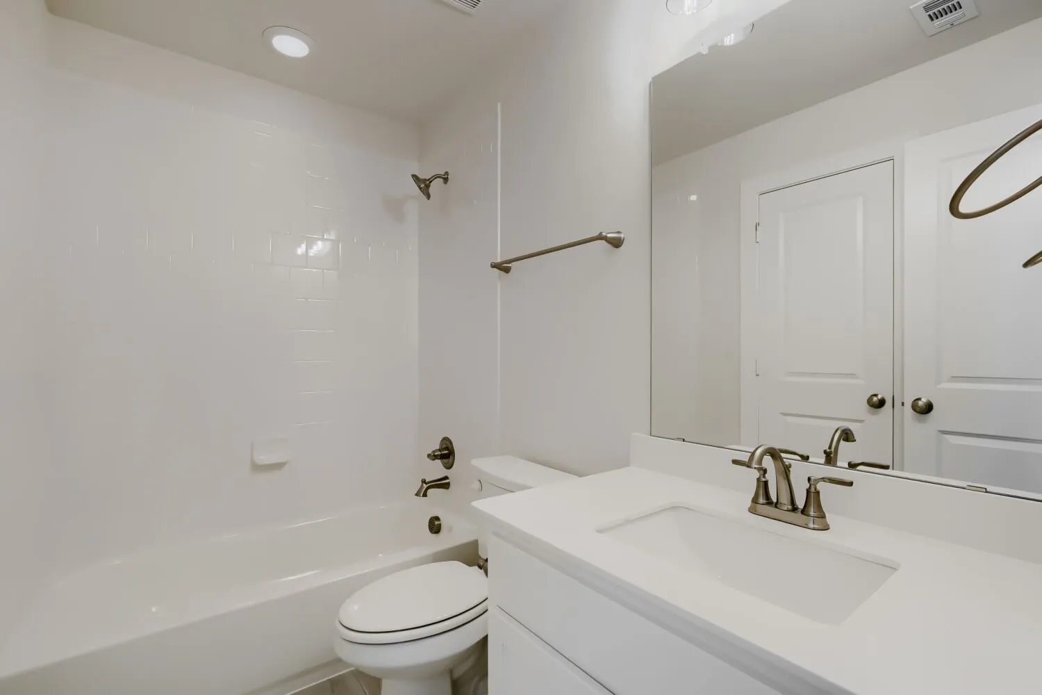 Bathroom featuring a vanity with an integrated sink, brushed nickel faucet, and a large mirror
