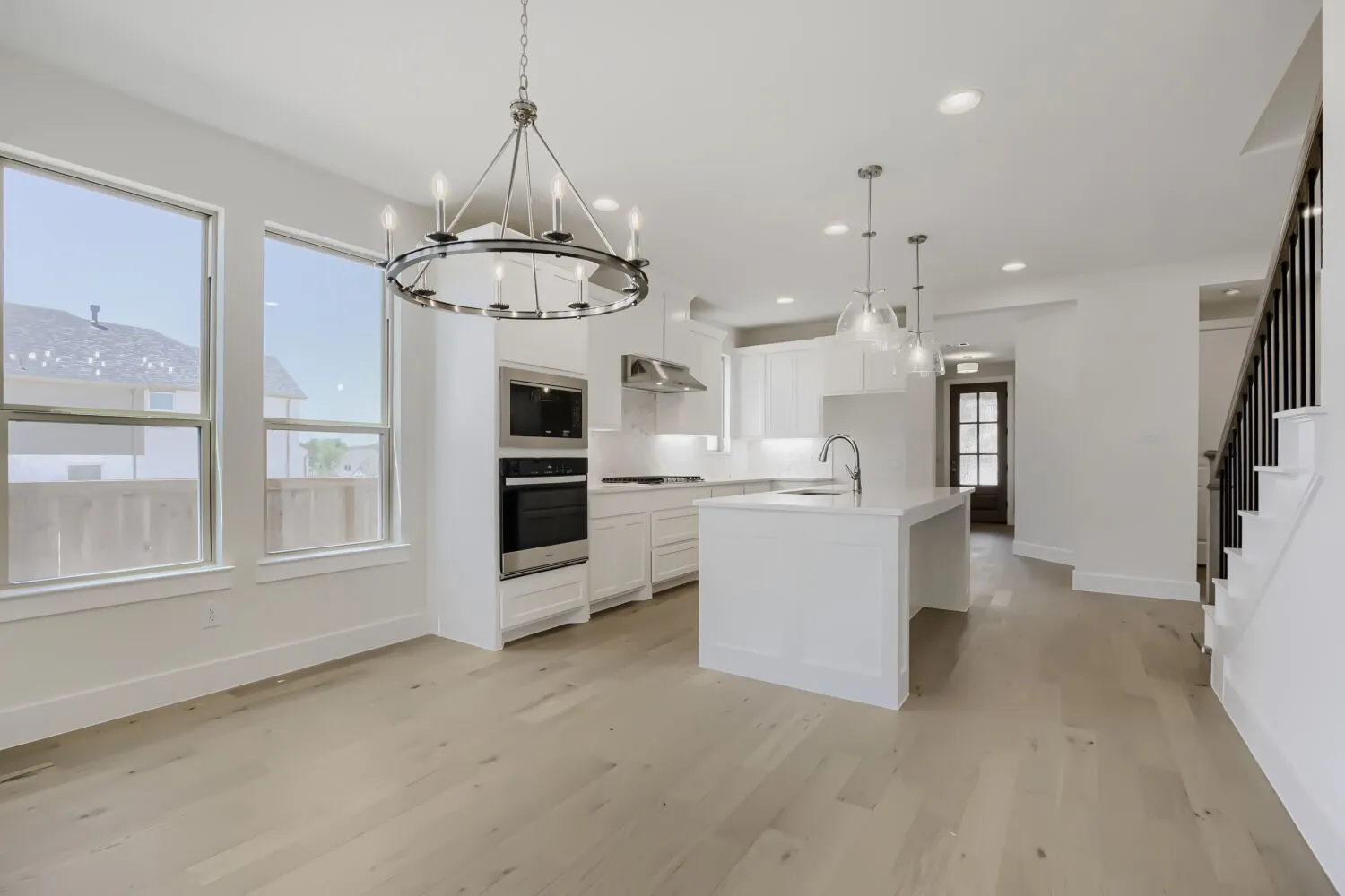 Open-concept living area featuring light wood-finish flooring and a contemporary chandelier