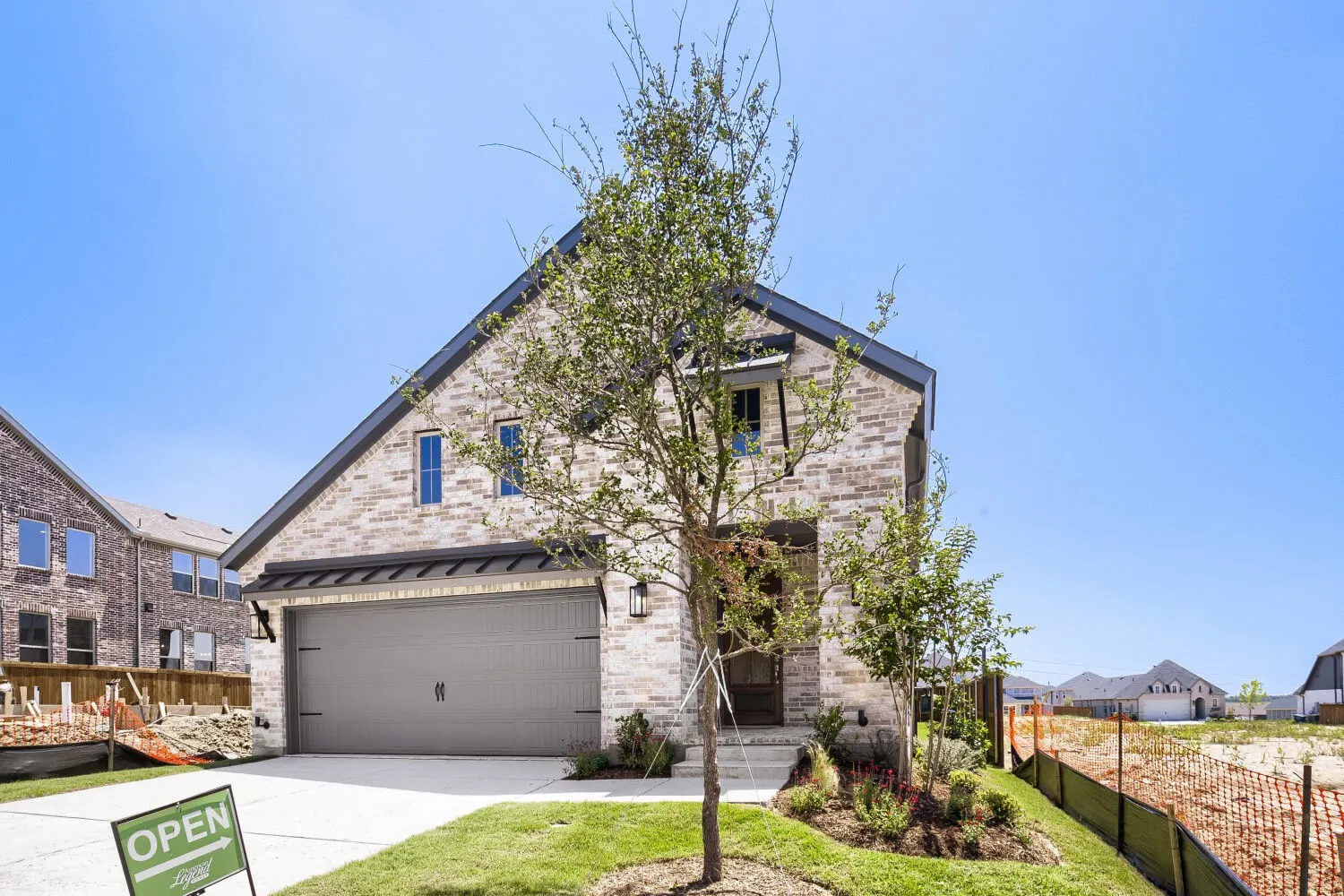 Contemporary brick facade with dark trim, featuring a prominent gable roofline and a two-car garage