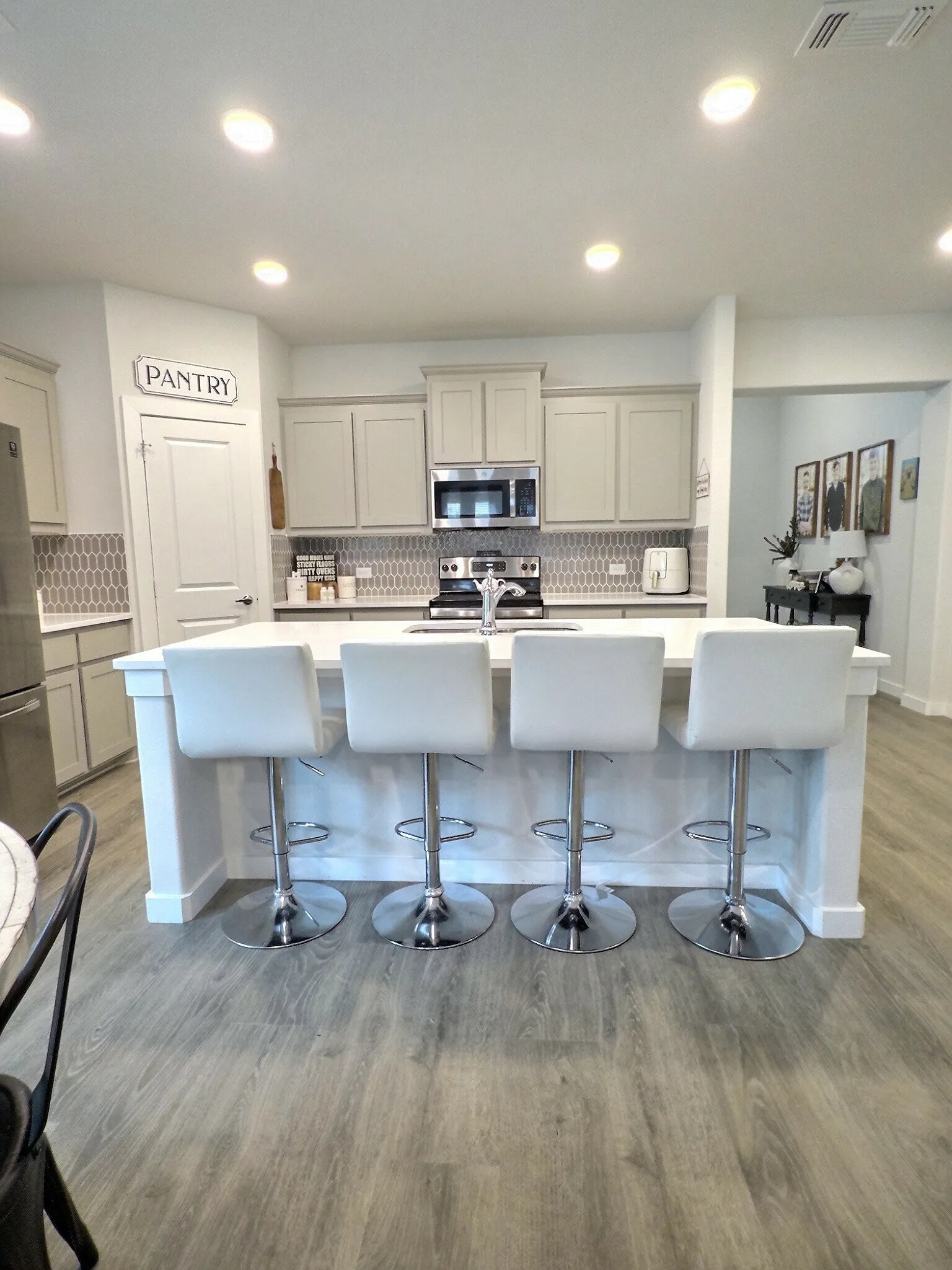 The kitchen features light-toned cabinetry, stainless steel appliances including an oven and microwave, and a stylish patterned backsplash