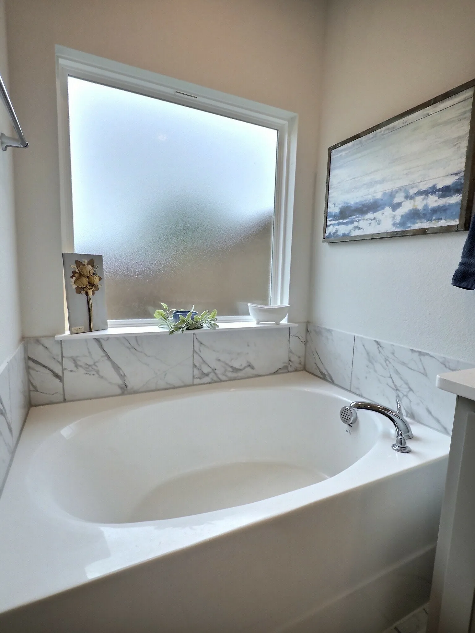 The bathroom features a built-in soaking tub with a polished chrome faucet and shower head, complemented by a marble-patterned tile surround