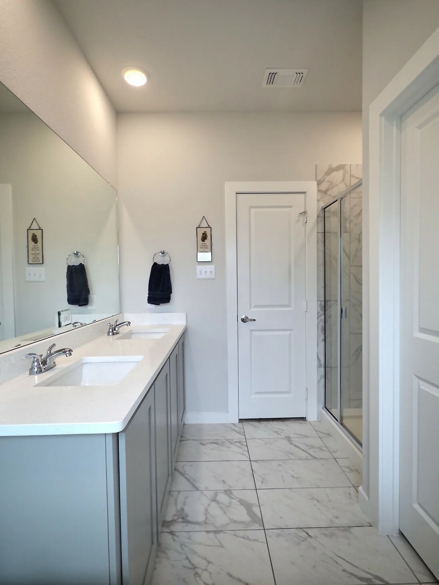 This well-appointed bathroom features a double vanity with light-colored countertops and undermount sinks, set against gray cabinetry