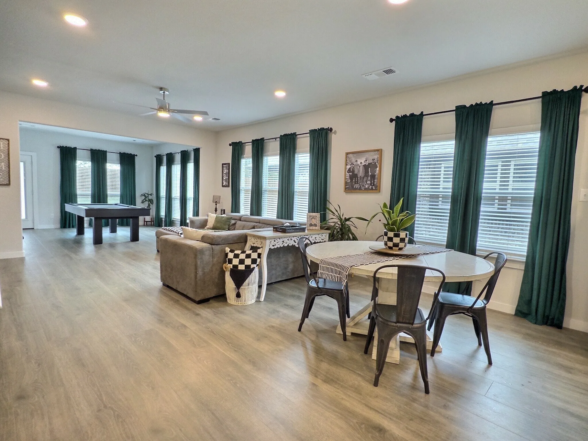 Spacious open-concept living area featuring light wood-style flooring, ample natural light from numerous windows, and recessed lighting