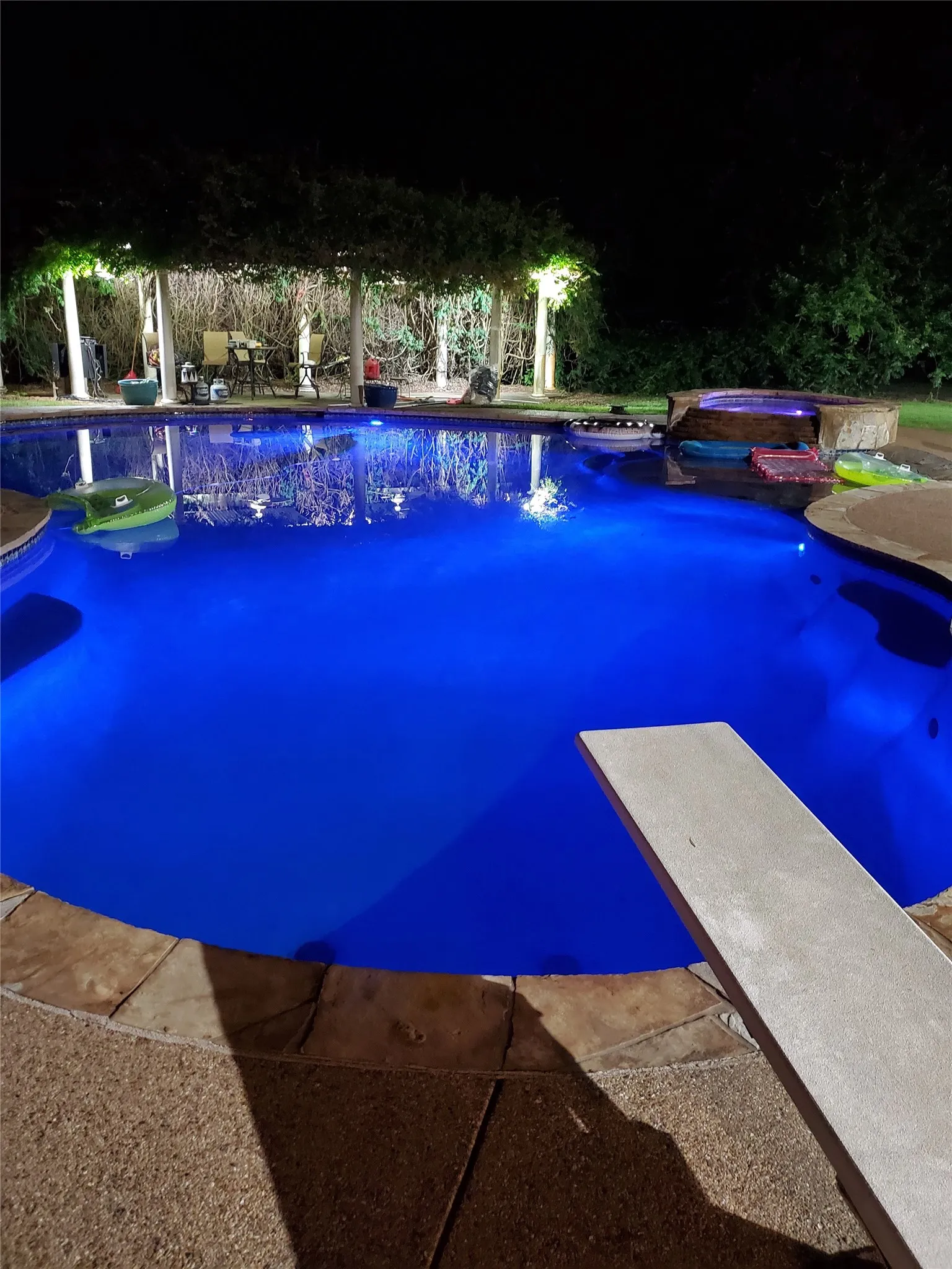 Pool at twilight with a diving board, an outdoor pool, and a jacuzzi