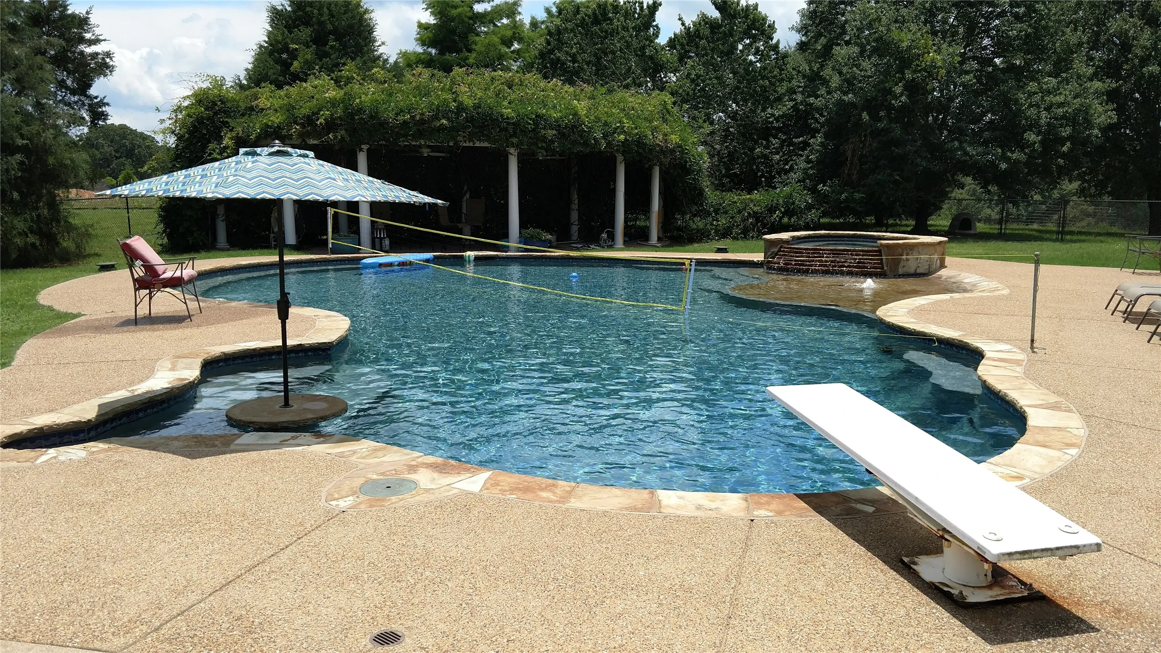 View of pool with a diving board, a patio, a fenced backyard, and a pool with connected hot tub
