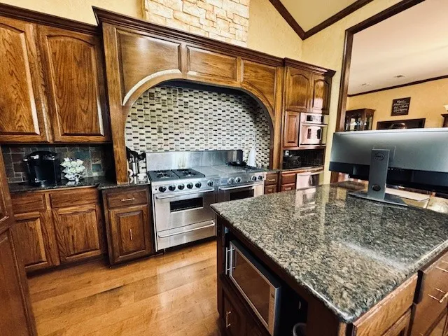 Kitchen featuring crown molding, tasteful backsplash, double oven range, and light wood finished floors