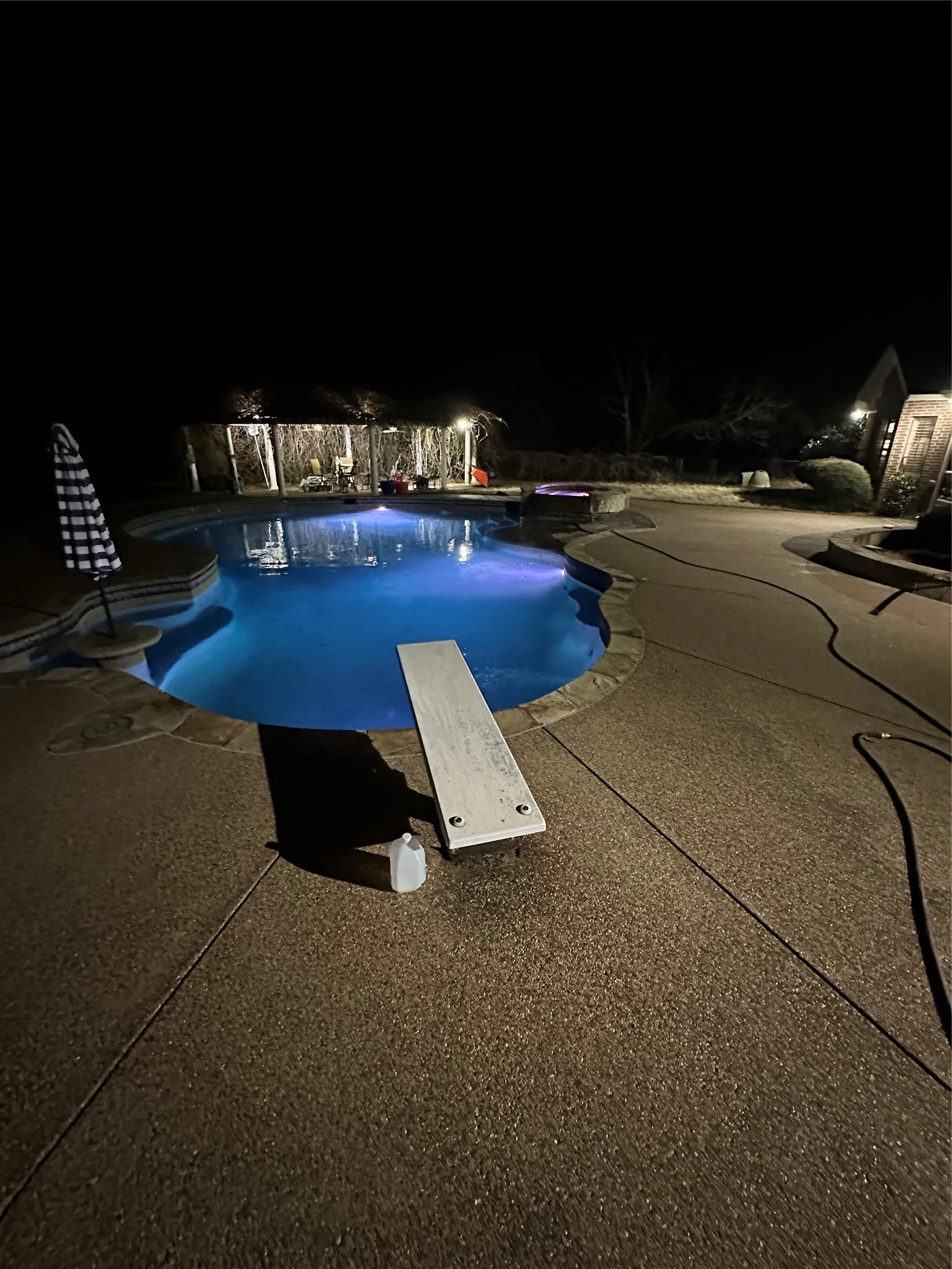 Pool at twilight featuring a diving board, an outdoor pool, and a patio area