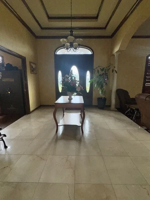 Foyer entrance featuring ornamental molding, a raised ceiling, and arched walkways