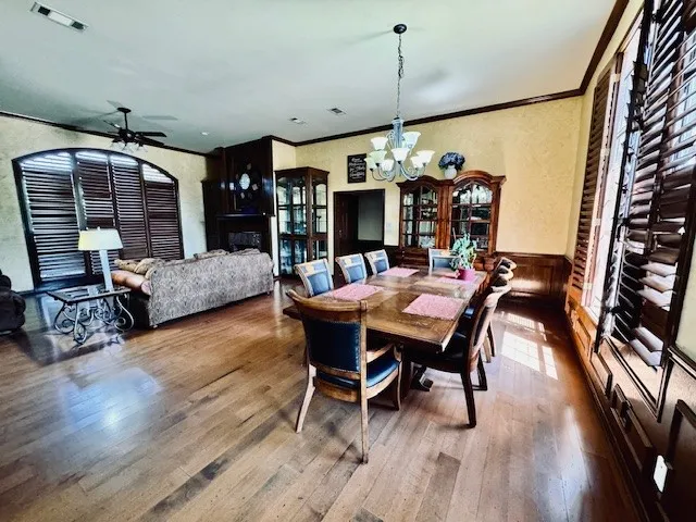 Dining space featuring crown molding, visible vents, a wainscoted wall, and wood finished floors