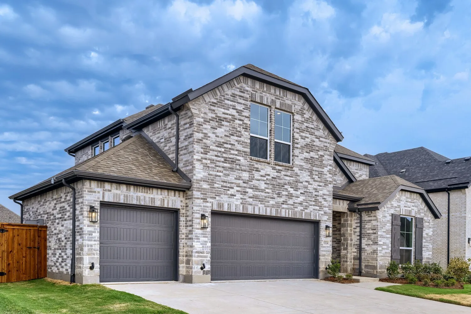 Brick exterior with dark gray trim, two-car garage, single-car garage, and a covered entry