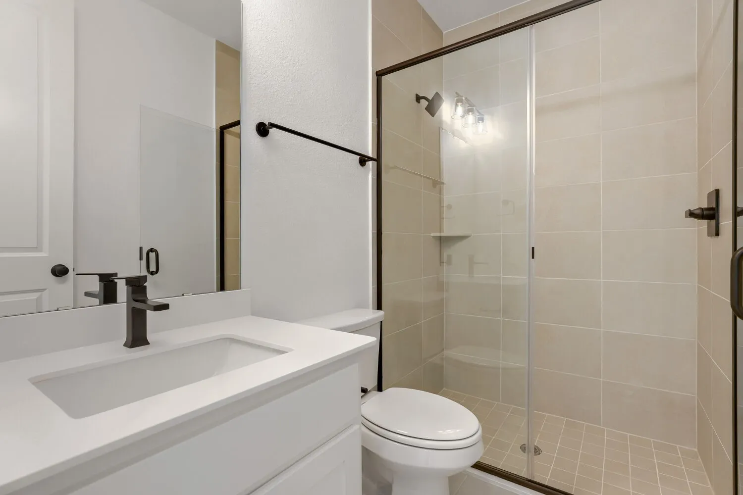 White vanity with an integrated rectangular sink, dark bronze faucet, and a frameless mirror