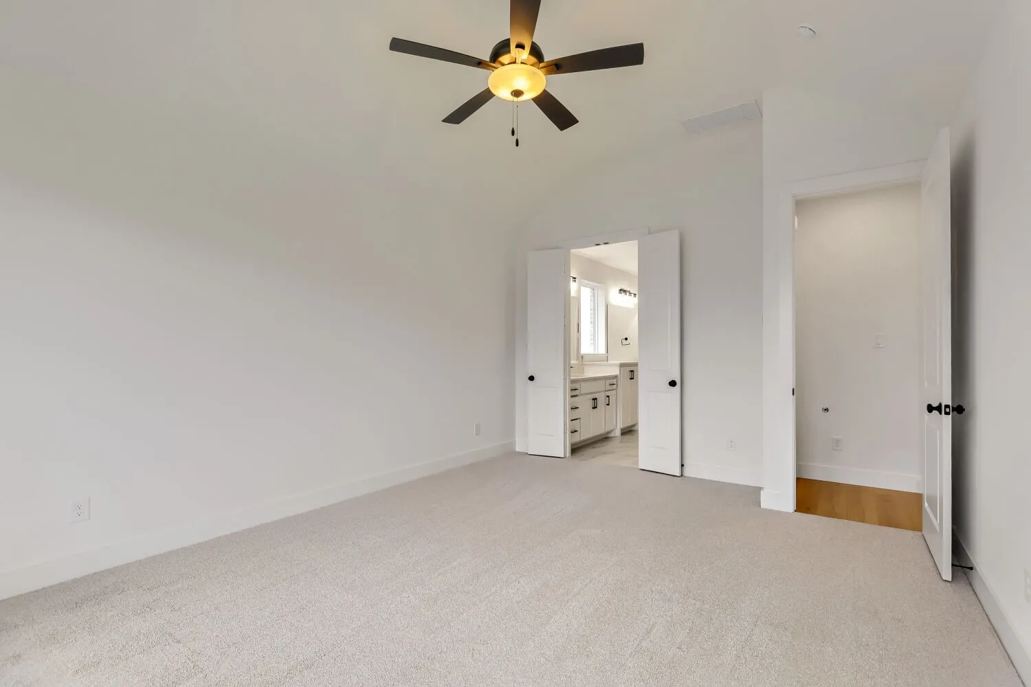 Carpeted flooring, ceiling fan with integrated lighting, double-door entry to a bathroom, white paneled doors, and light-toned walls