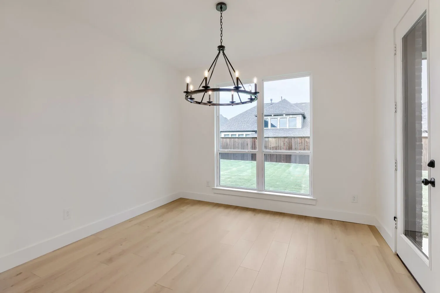 Wood-finish flooring, white walls, and a contemporary chandelier