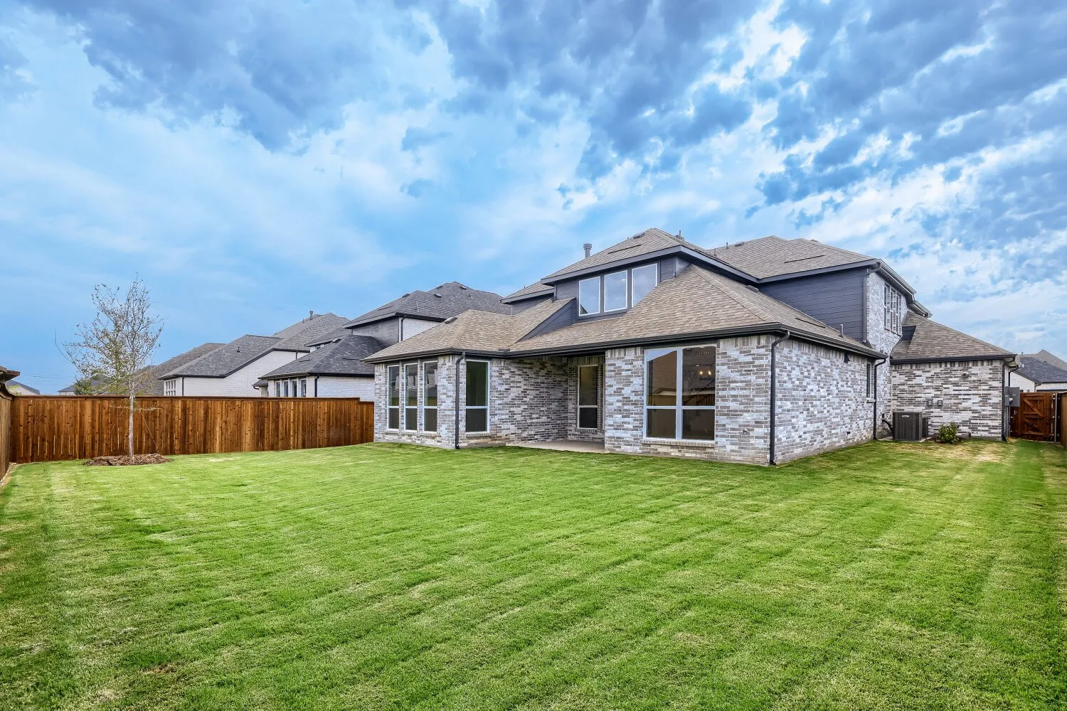 Expansive backyard featuring a lush lawn, privacy fencing, and a stone and siding exterior