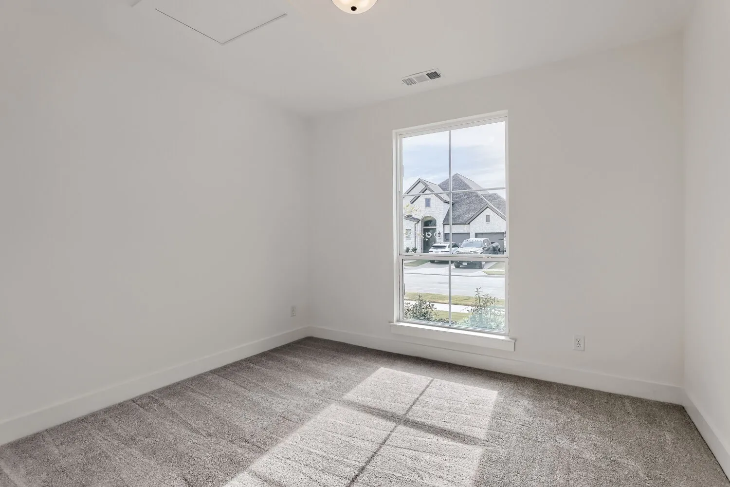 Neutral wall paint, gray patterned carpet, white trim, and a single-pane window