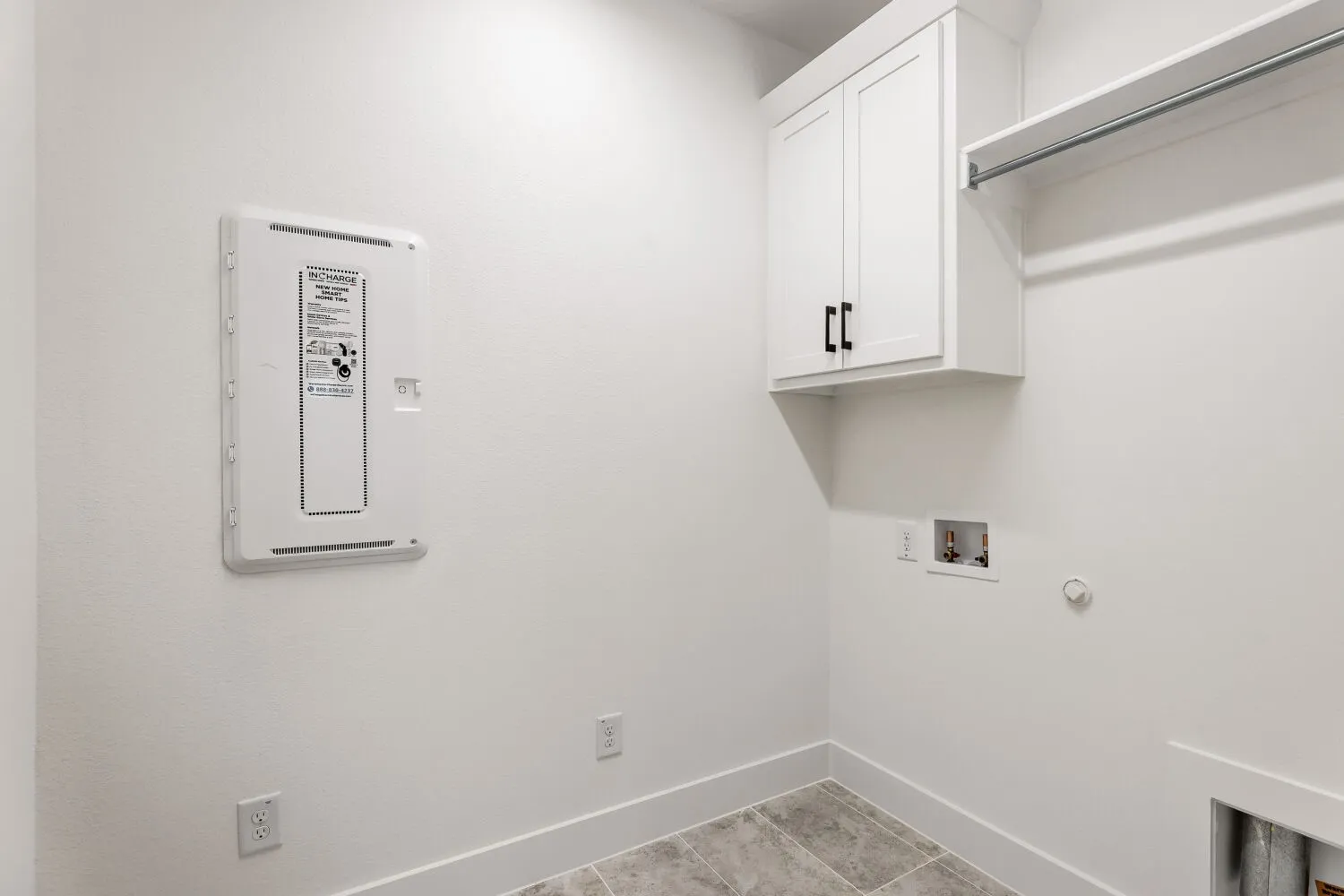 White shaker-style cabinetry with matte black hardware, integrated hanging rod, and tile flooring