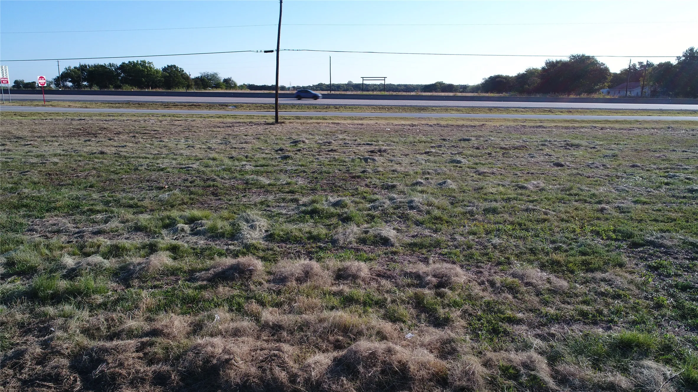 The property features a cleared lot with a mix of green and dry grasses