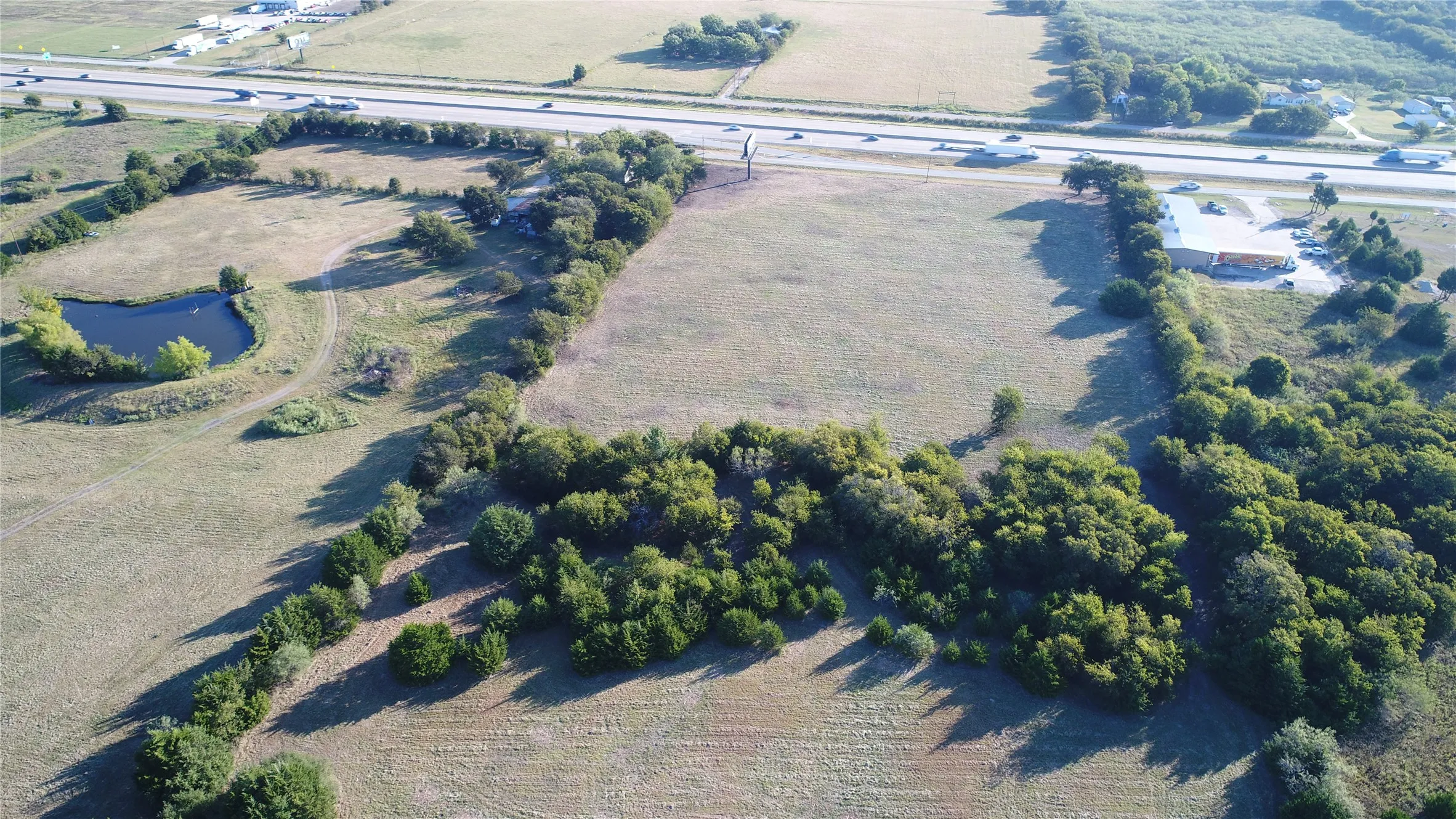 Expansive property featuring verdant fields, a natural pond, and mature tree lines