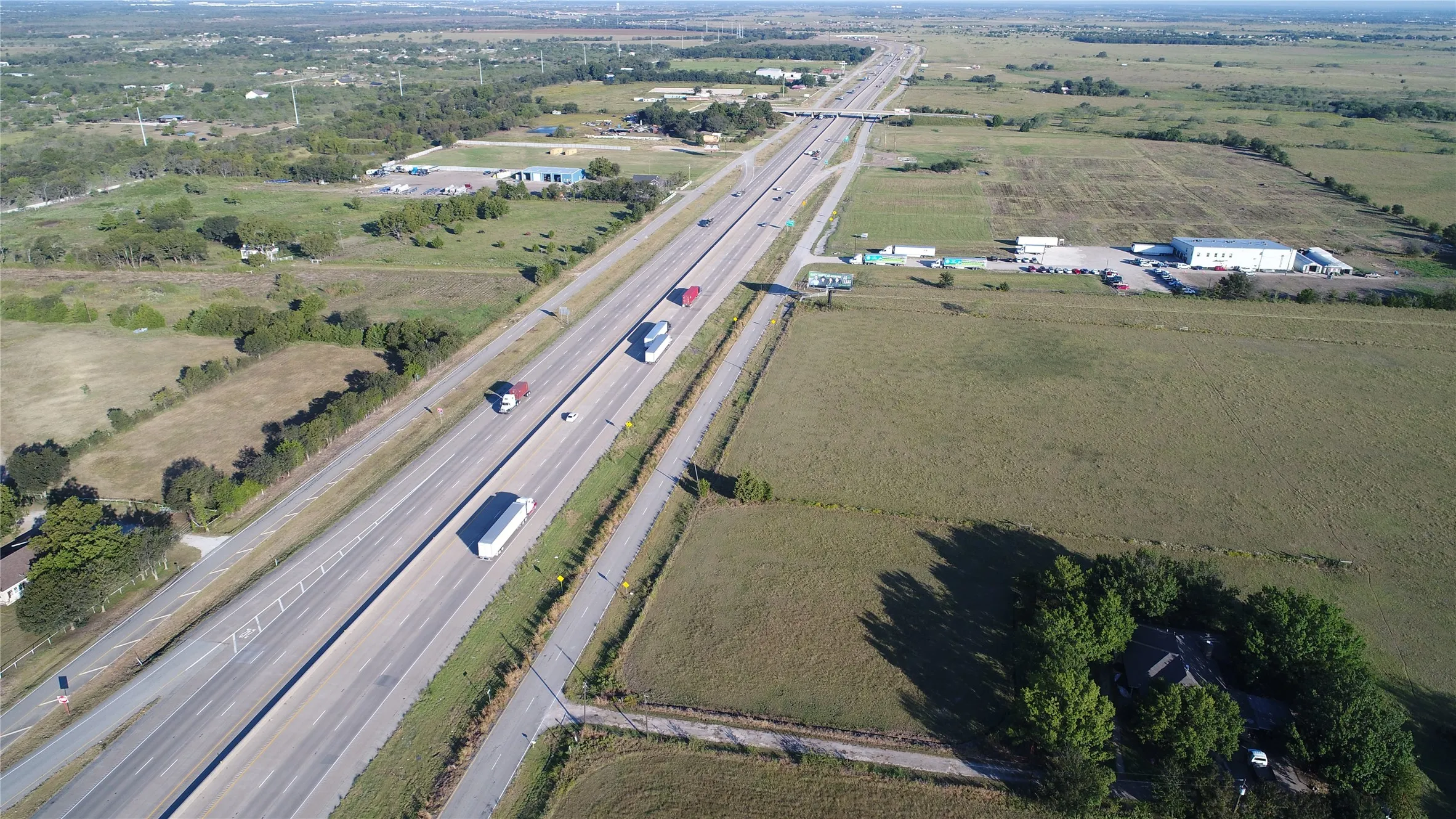 Aerial view showcasing a nearby highway, green fields, and surrounding trees