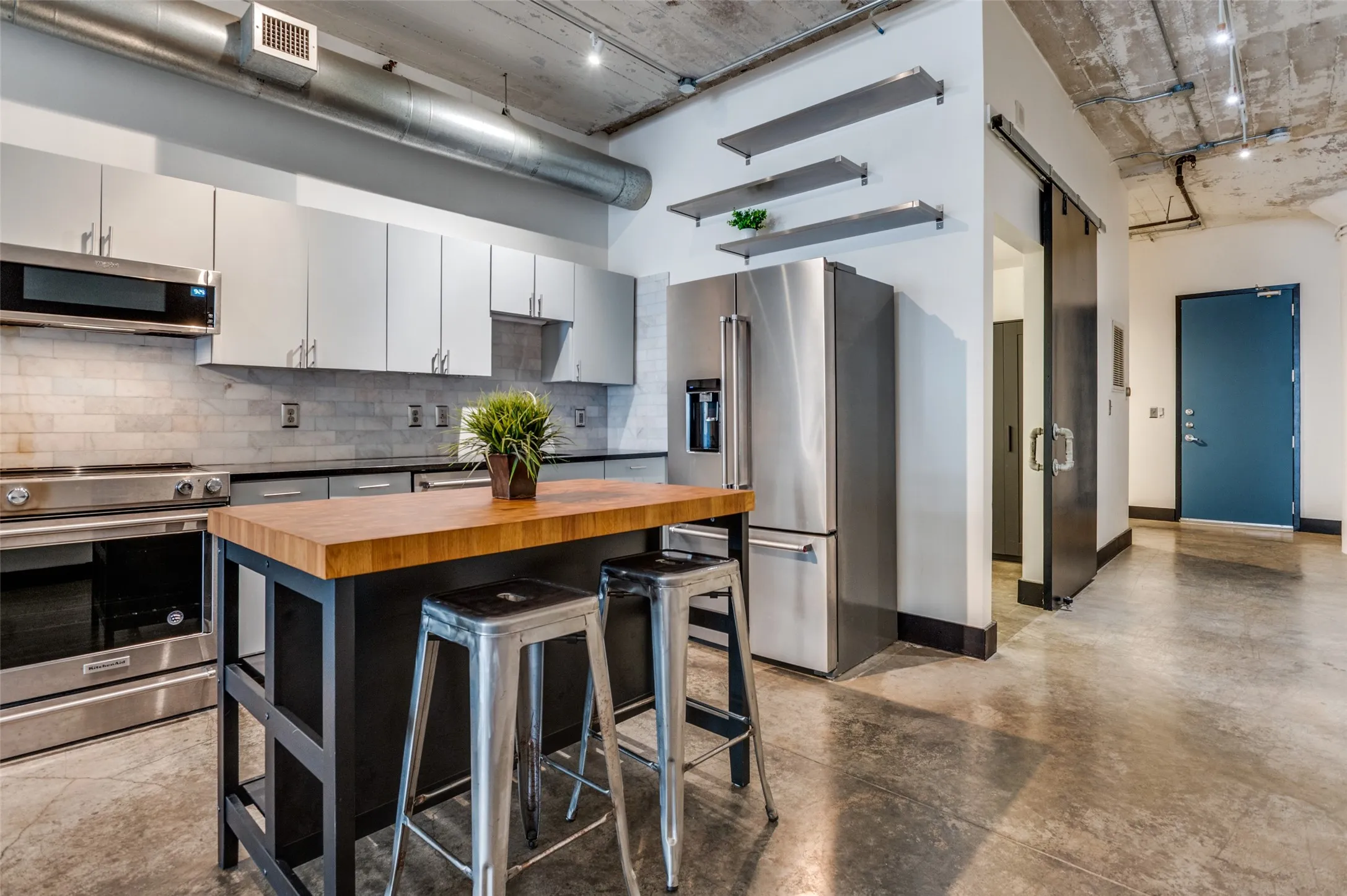 Super cute open loft with cement floors, butcher block island, updated modern cabinetry and a private restroom