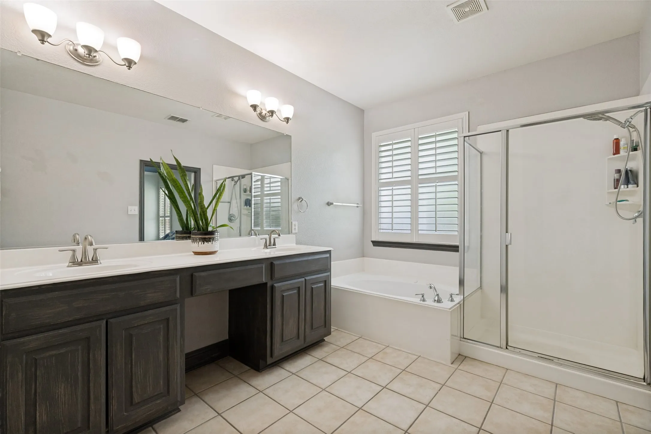 Tiled master bathroom equipped with jetted tub, separate oversized shower, dual sinks, vanity and walk-in closet.