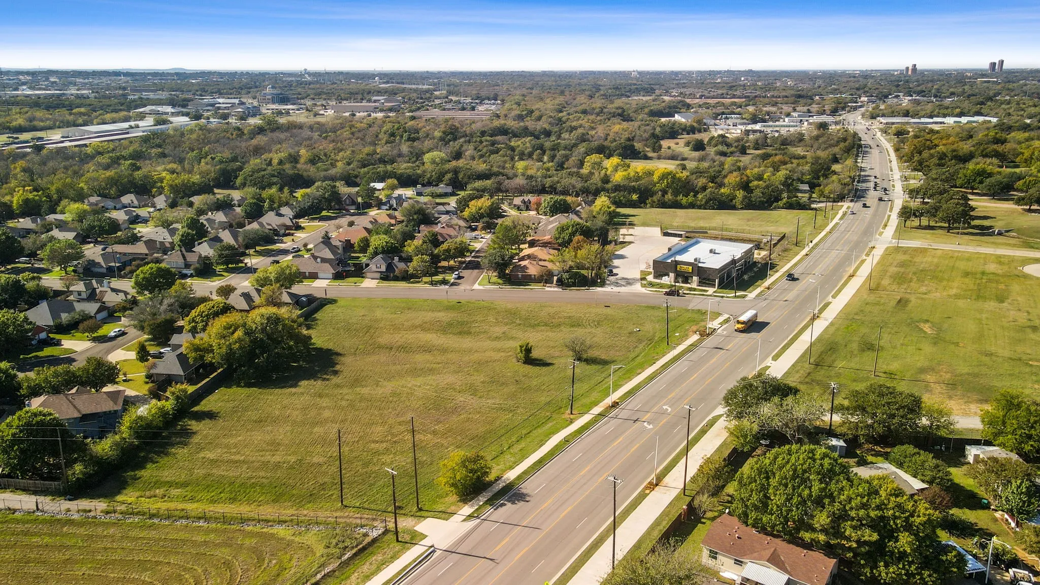 Expansive lot with a lush green lawn, offering a clear view of the surrounding neighborhood and a nearby commercial building