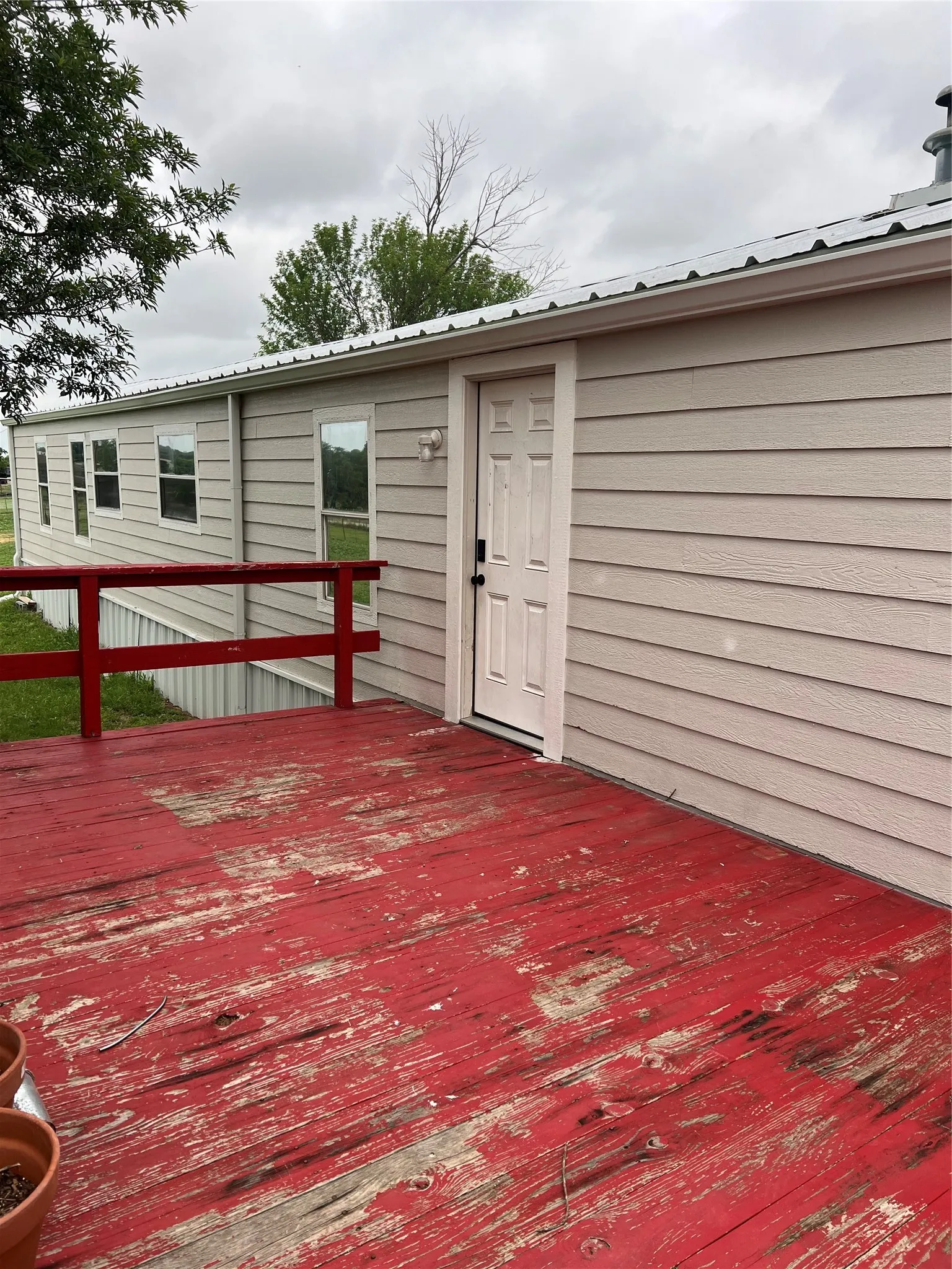 The property features exterior siding, a white entry door, and a red deck